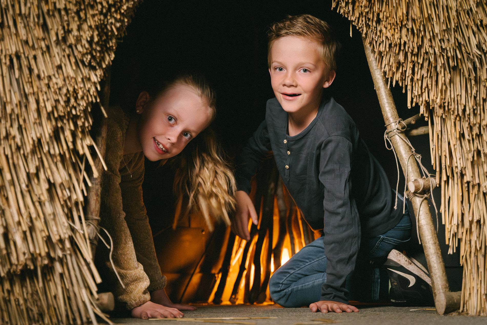 Två barn som kikar ut ur en vasshydda.