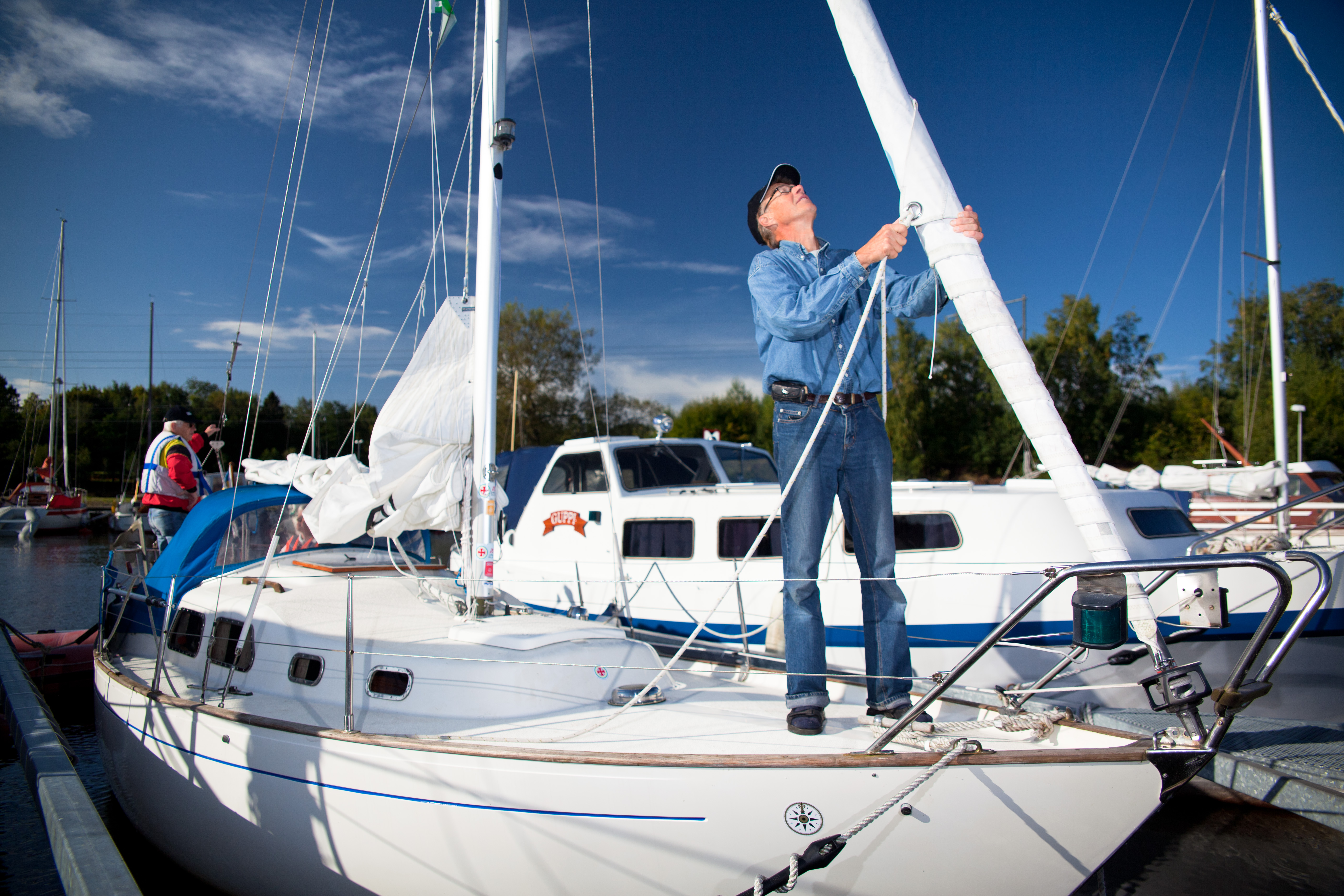 En man som tar ner segel på sin vita båt