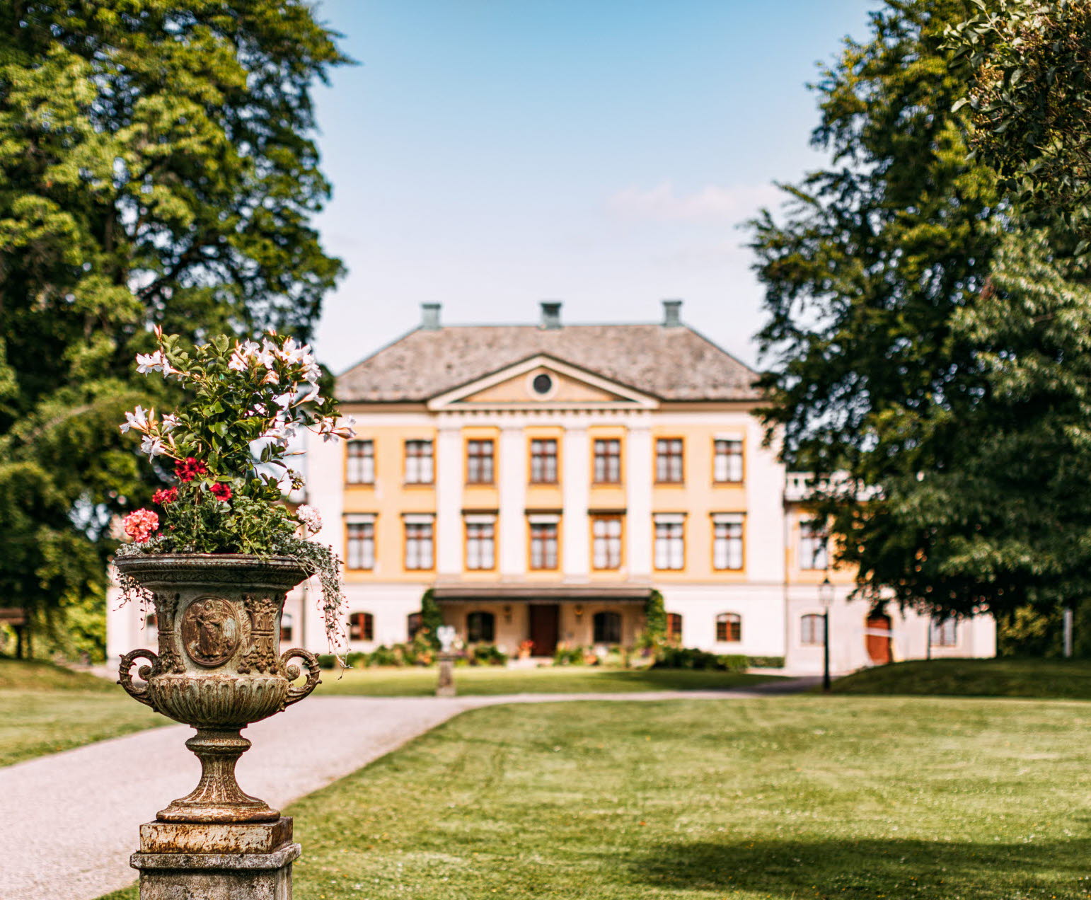 A yellow mansion with large trees at the sides
