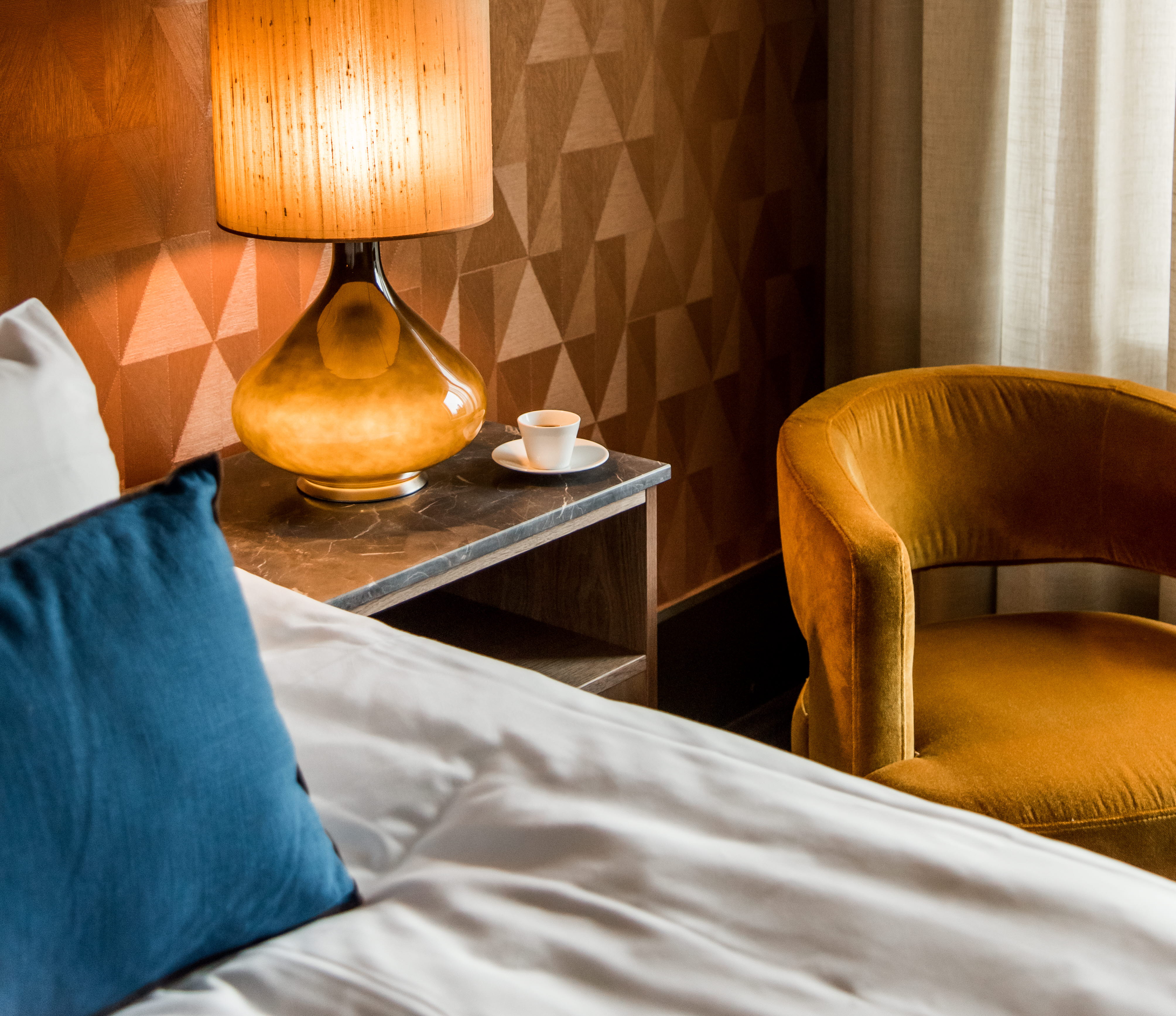 Ett hotellrum med ett sängbord med en stor lampa