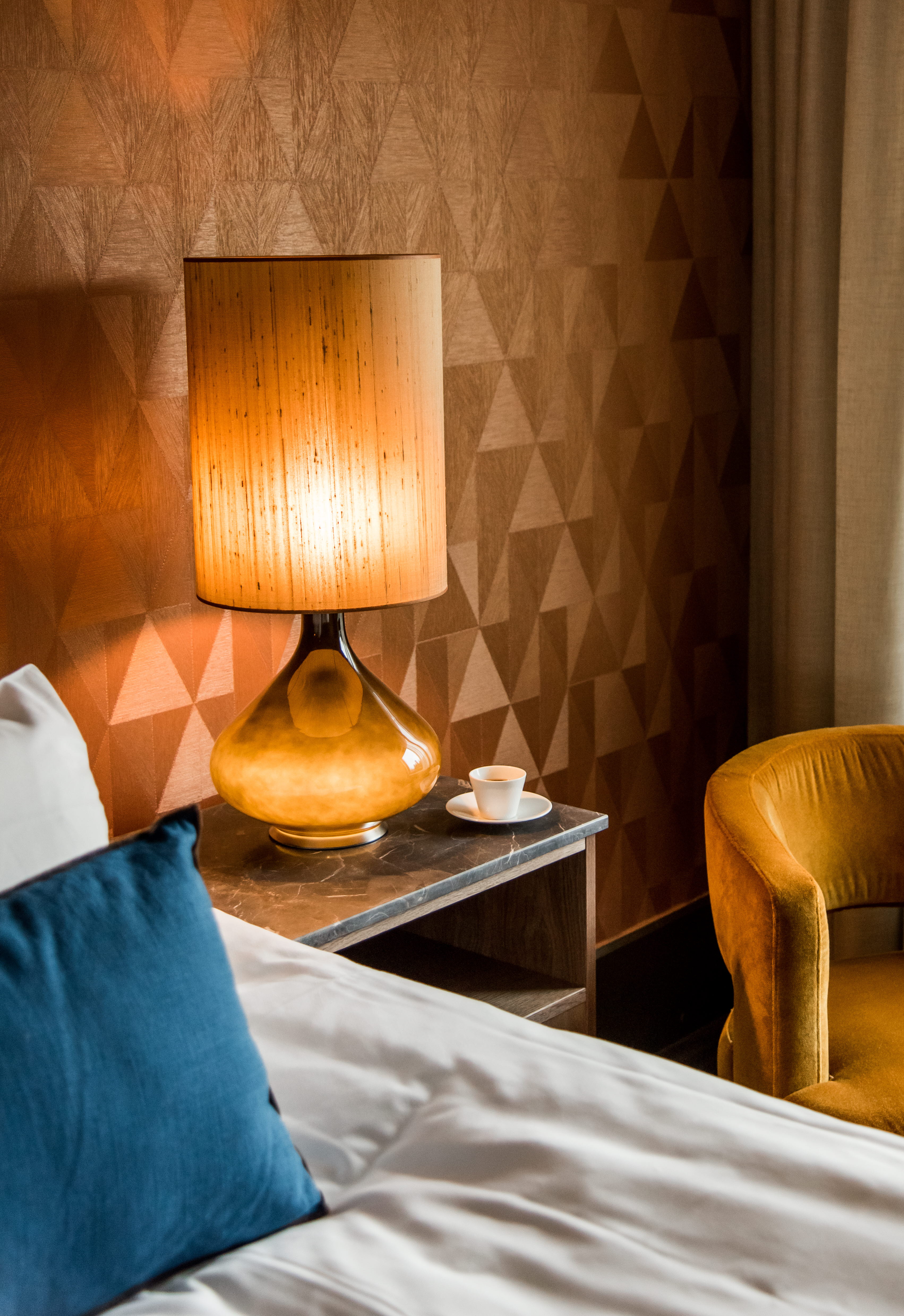 Ett hotellrum med ett sängbord med en stor lampa