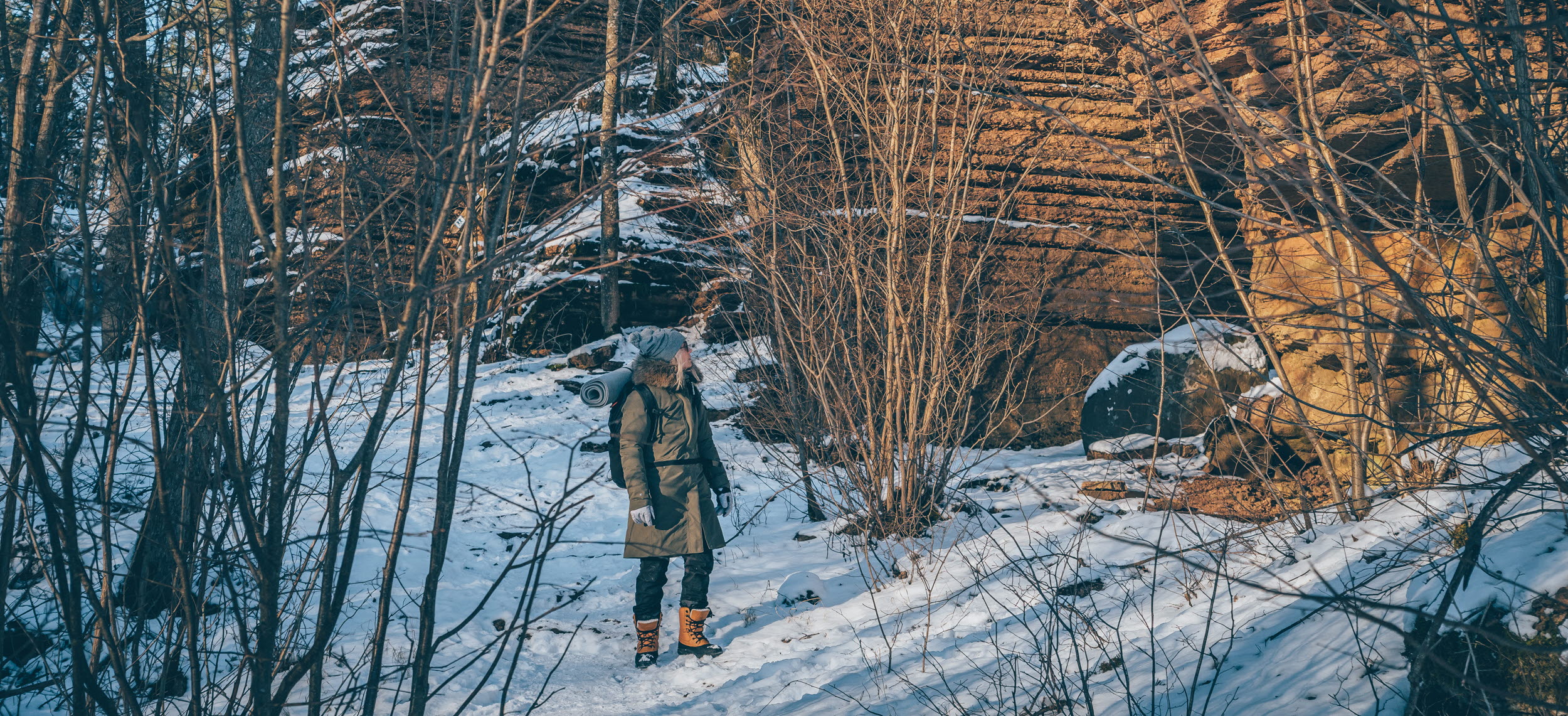 En kvinna som går omkring bland stenformationer i ett vintrigt landskap