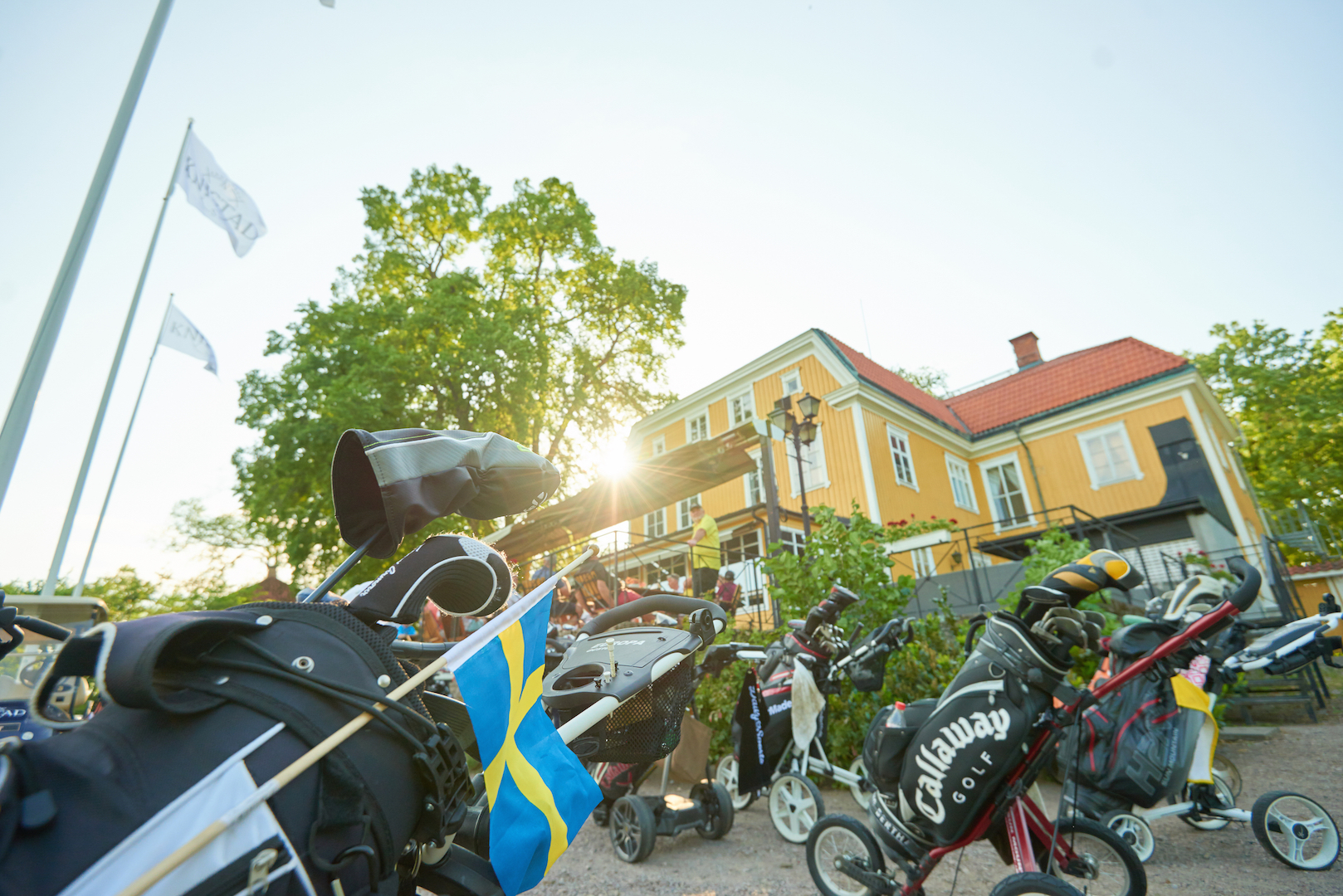 Golfutrustning och en herrgårdsbyggnad i motljus