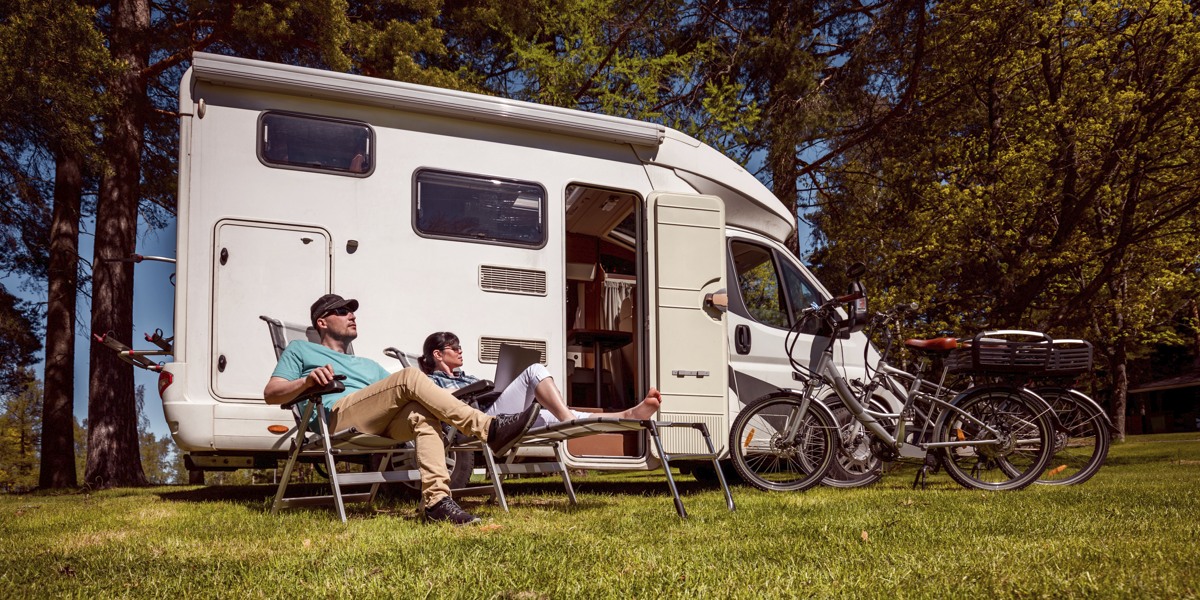 En man och en kvinna sitter utanför en husbil