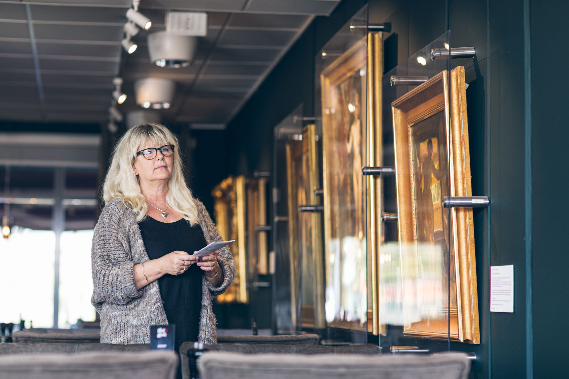 En kvinna tittar på tavlor på ett konstgalleri