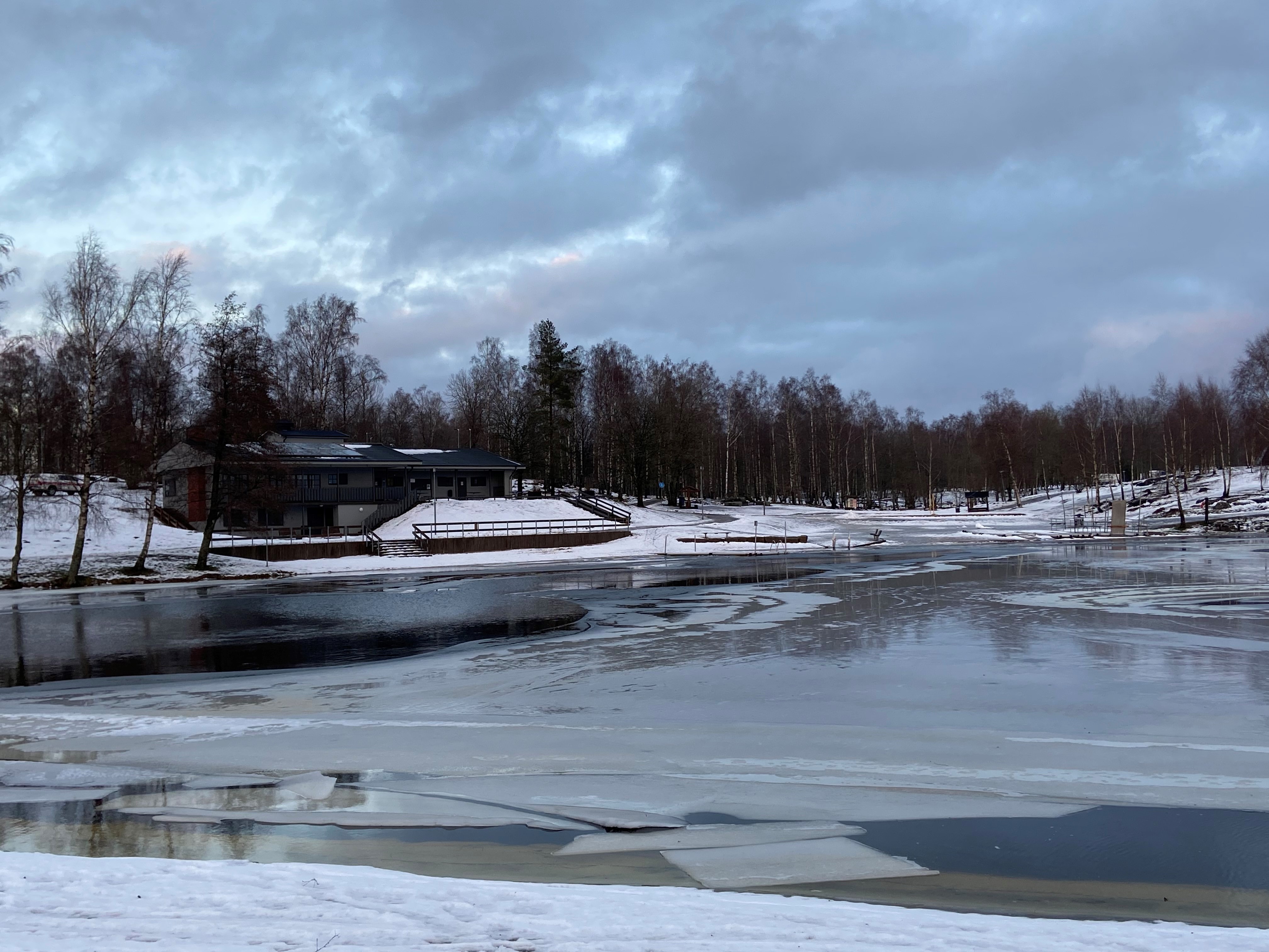 sjö med vatten och is. Motionscentralen i bakgrunden.