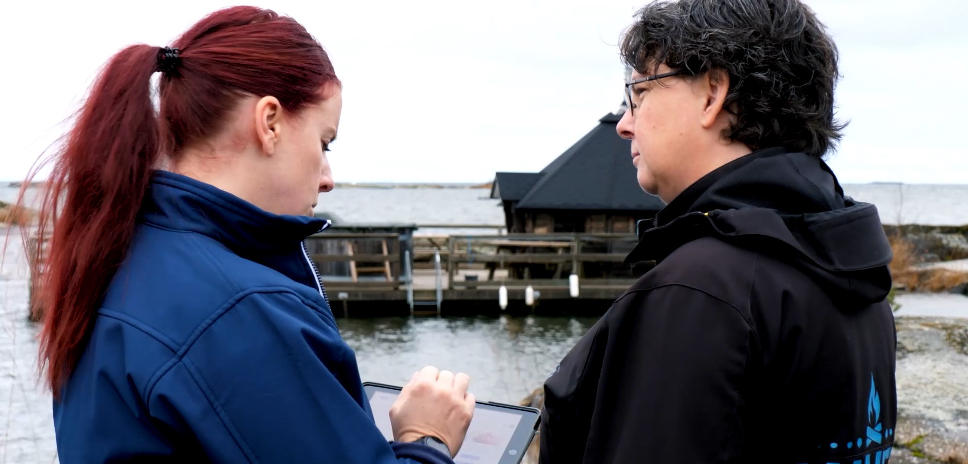 Två kvinnor pratar med varandra i närheten av en sjö