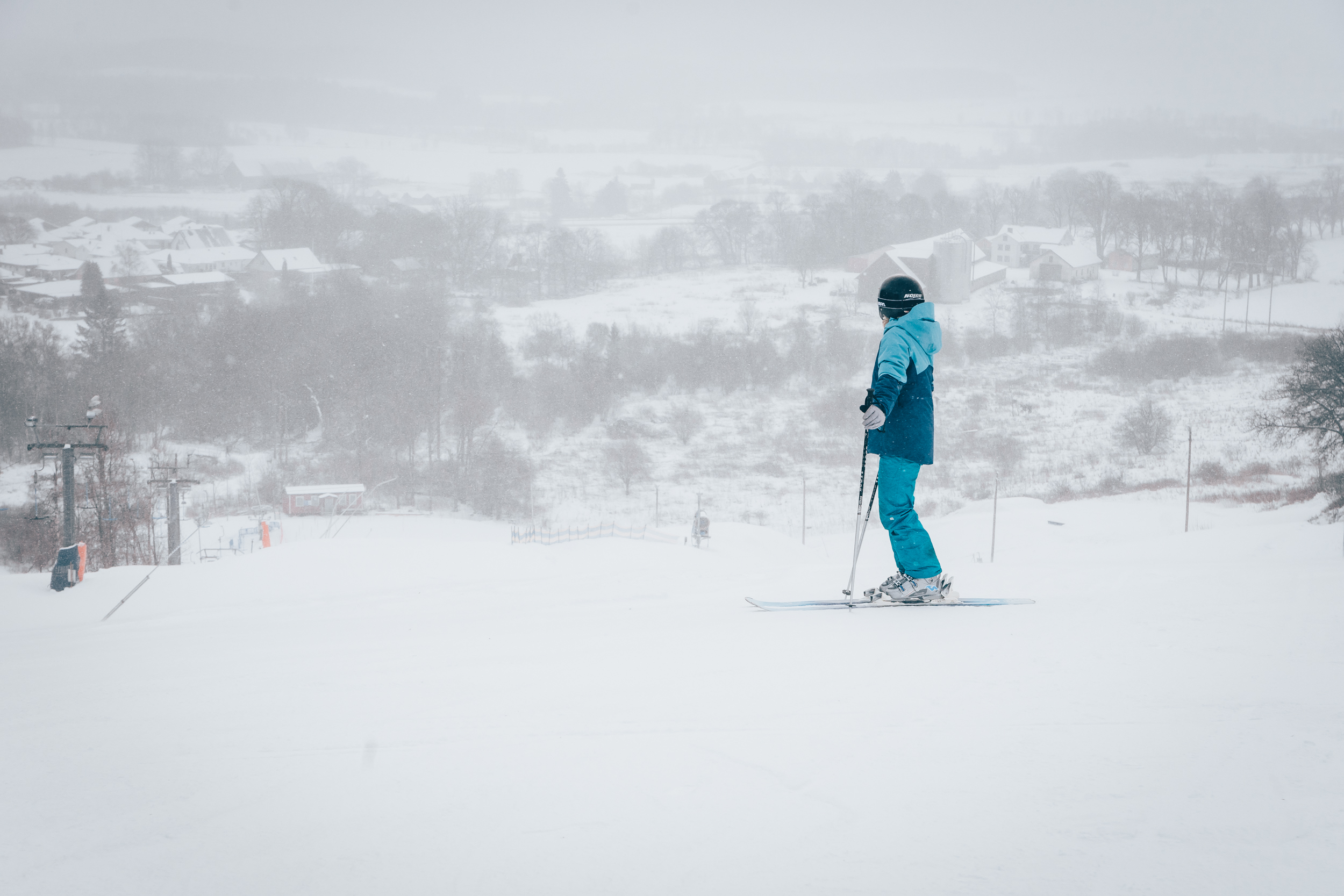 En pojke i blåa skidkläder som tittar nerför en slalombacke
