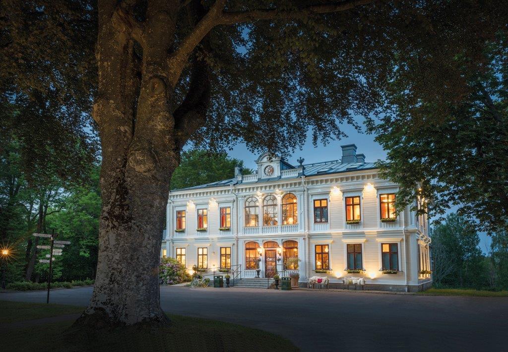 En stor gul byggnad där lampornas sken från fönstren lyser upp i mörkret. 