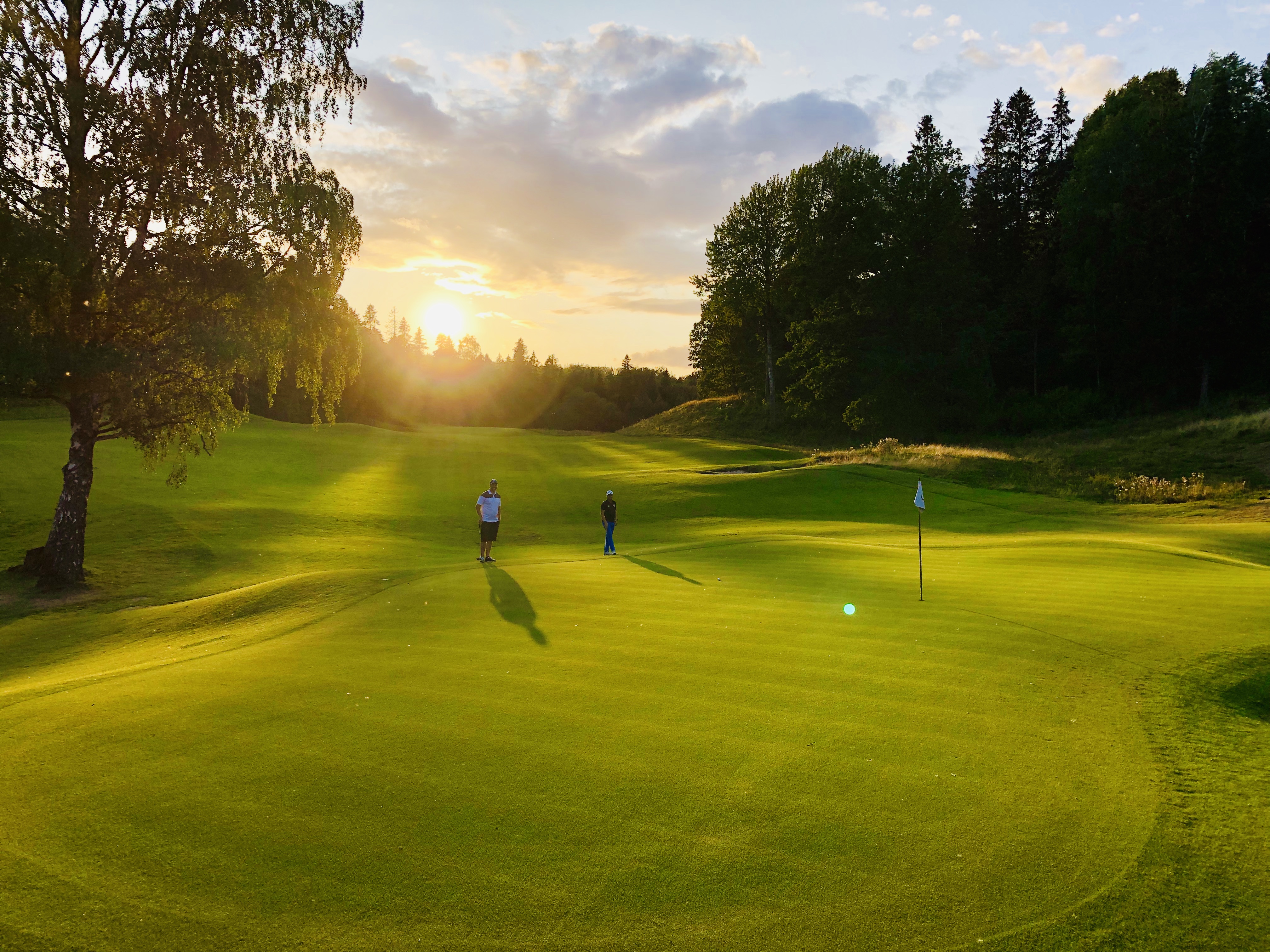 Skövde golfklubb, två peroner som spelar golf i solnedgång