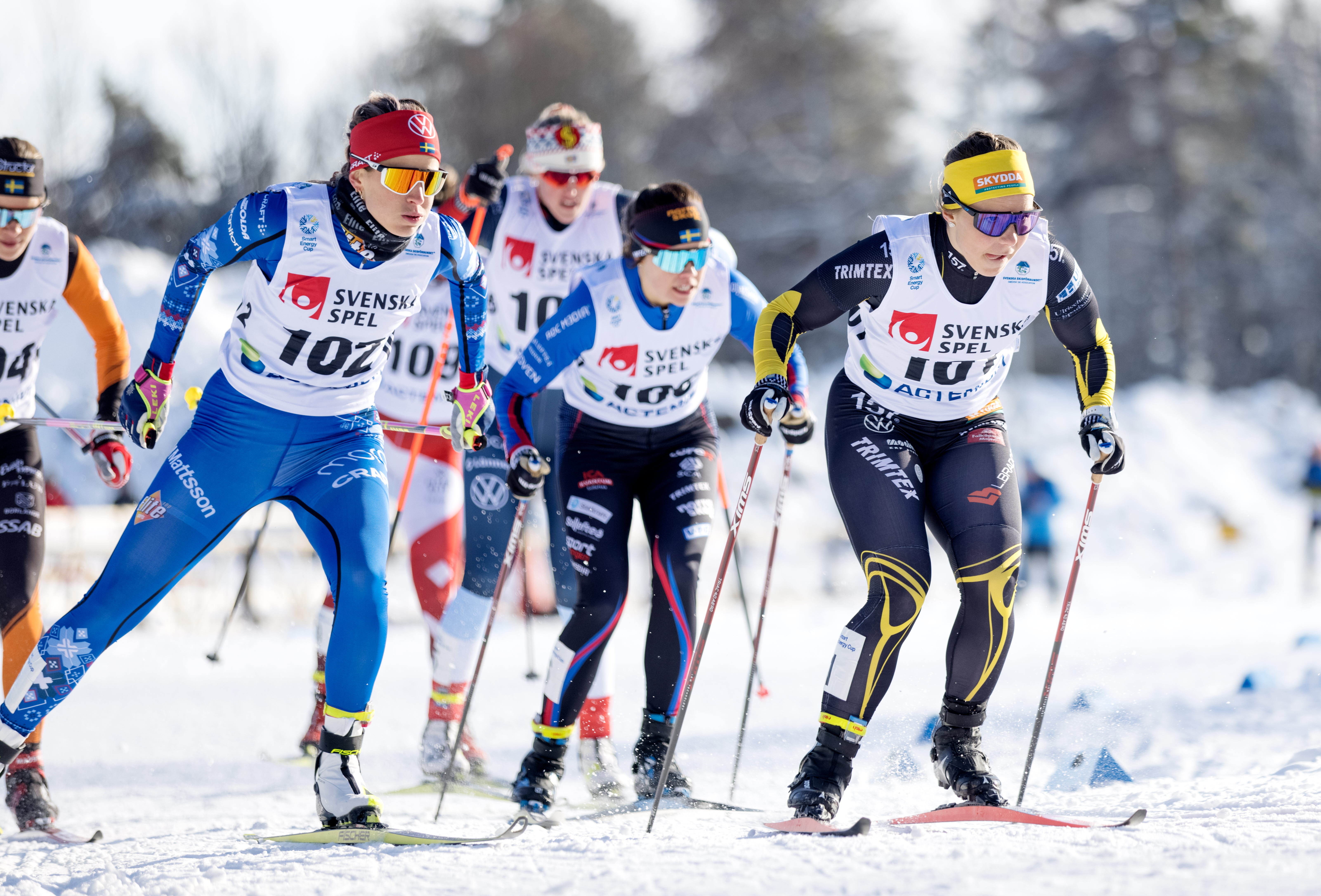 Tävlande längdskidåkare i fullt fokus på väg in i en kurva.
