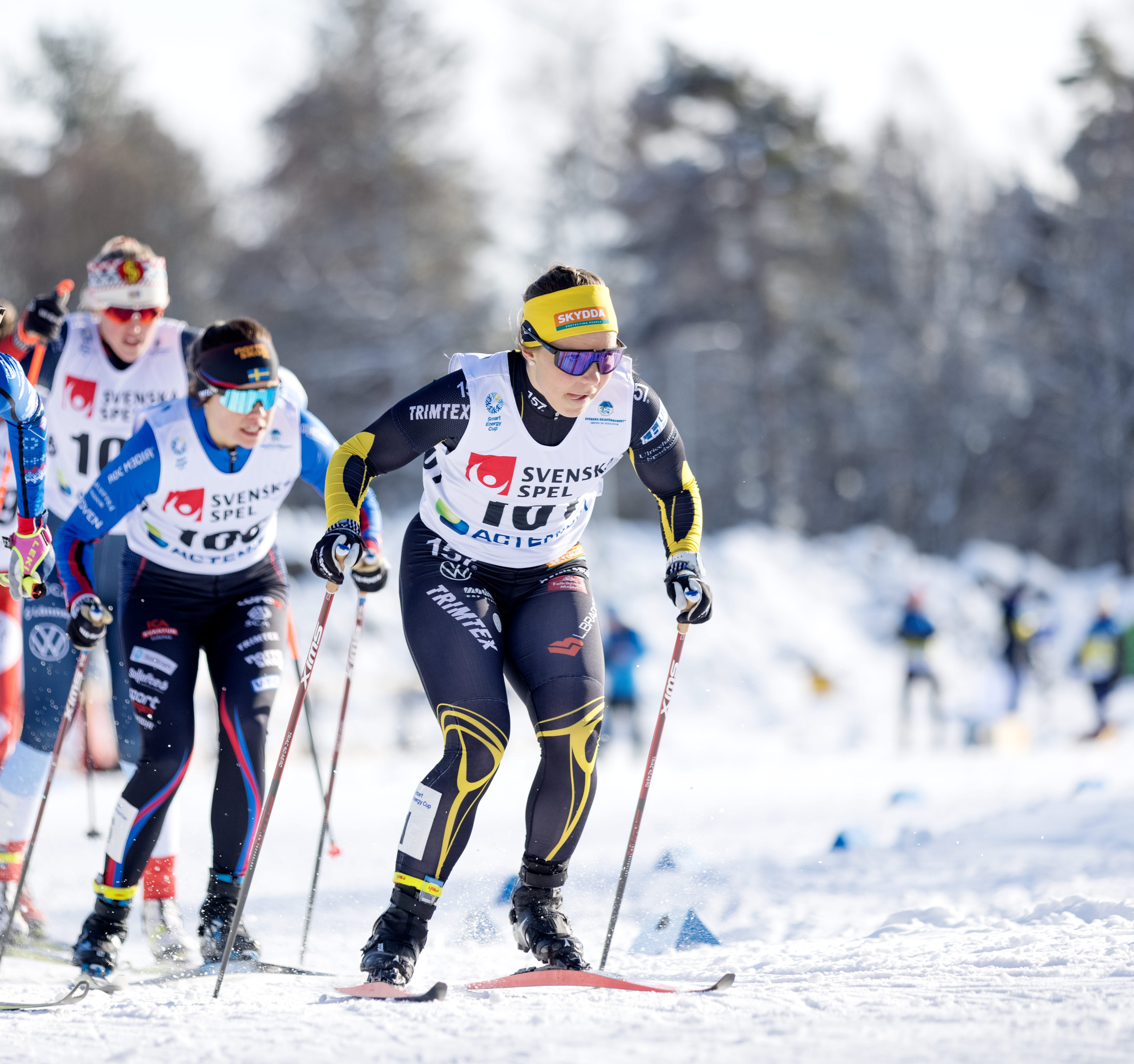Tävlande längdskidåkare i fullt fokus på väg in i en kurva.