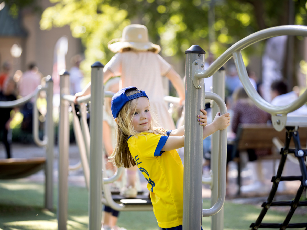 En kille med sveriget-shirt och blå keps leker i en lekpark.