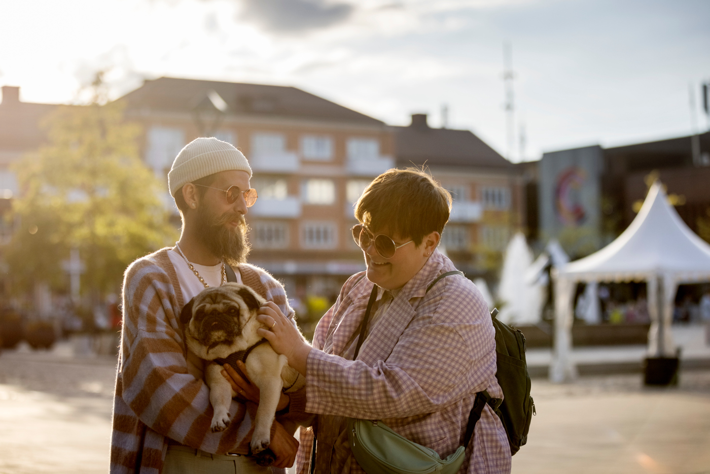 En man och kvinna på ett torg med en kund i famnen.