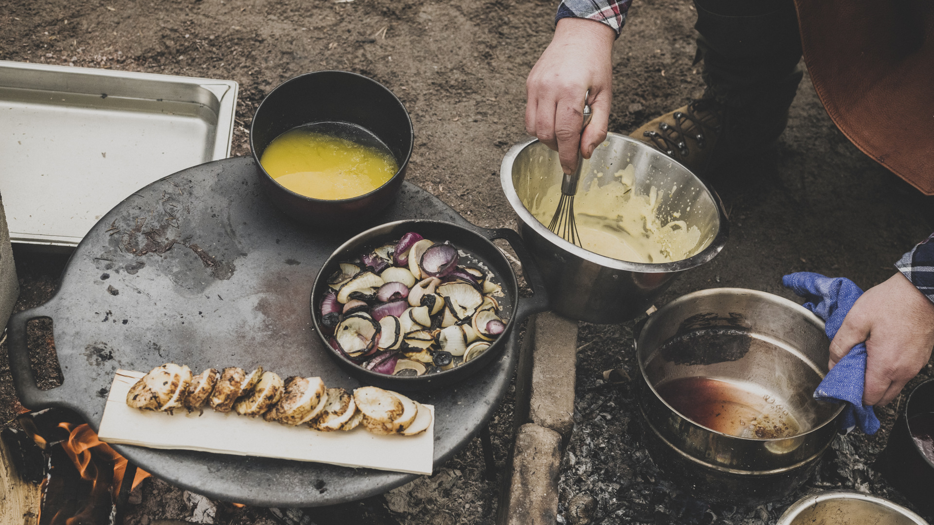 En person lagar mat över öppen eld