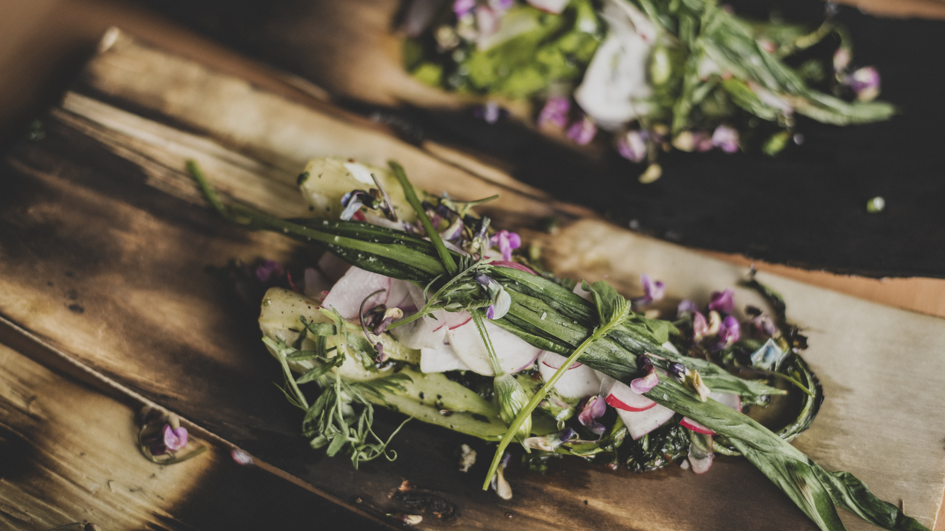 En färgglad rätt tillagad på lokala råvaror ligger framdukad på ett träunderlag.