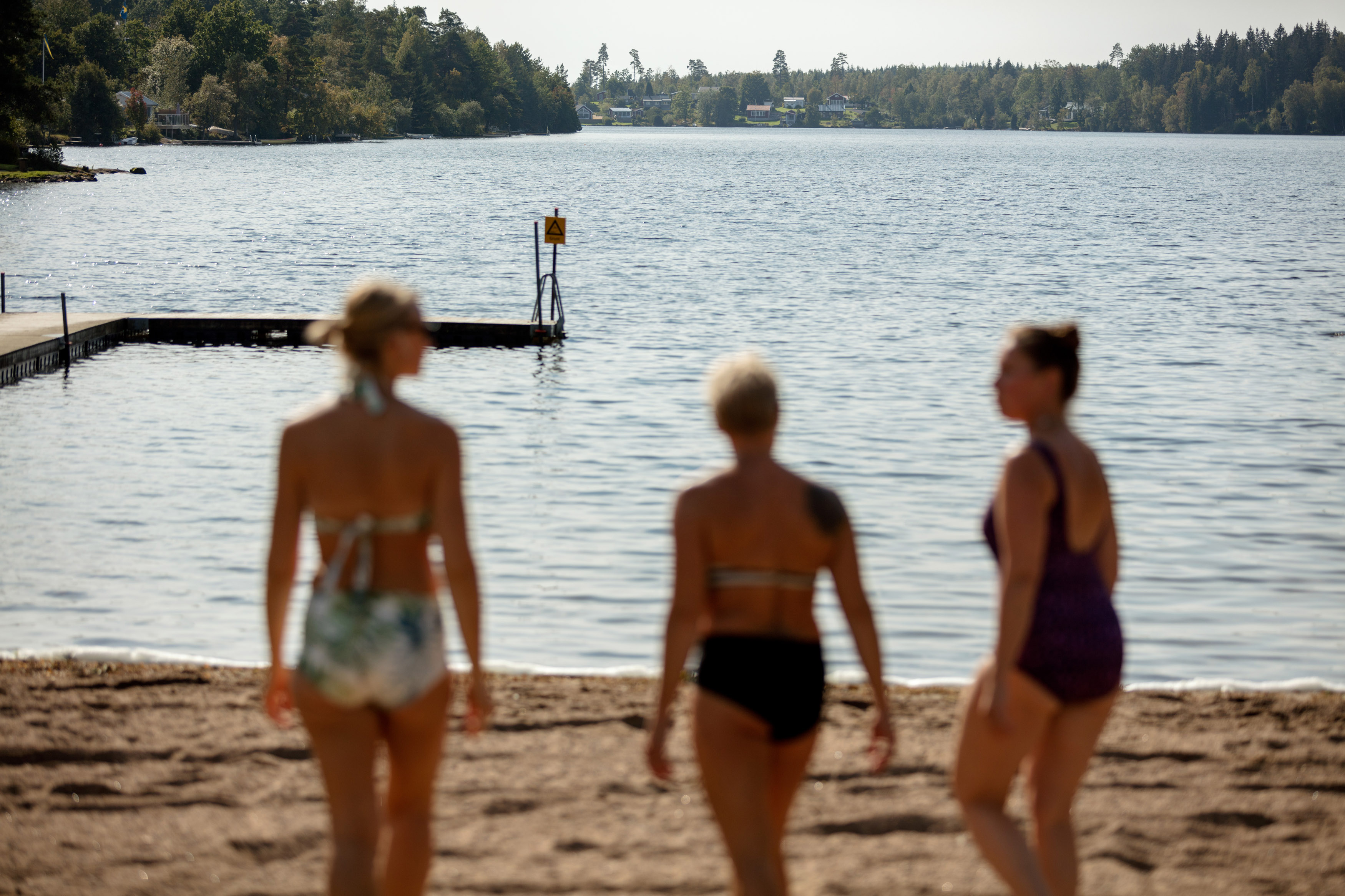 Tre kvinnor är påväg ned till sjön för att bada.