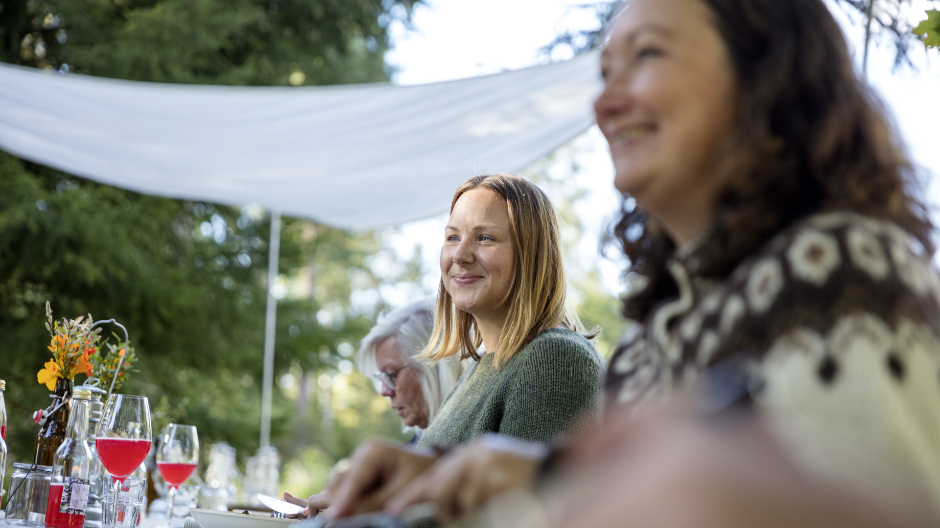 Två leende kvinnor sitter vid ett dukat bord.
