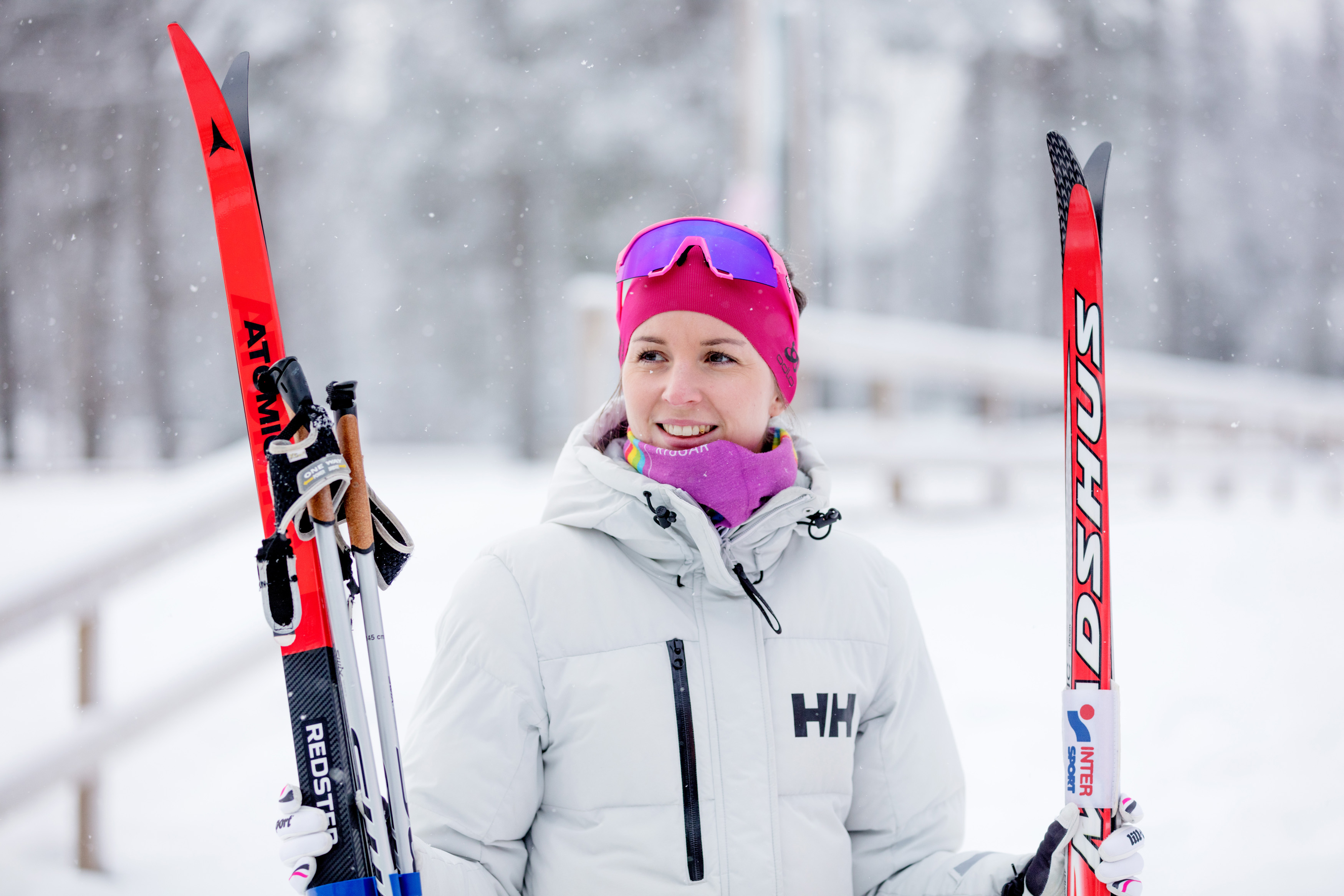 En skidåkare står i vinterlandskap med skidor och stavar i handen.