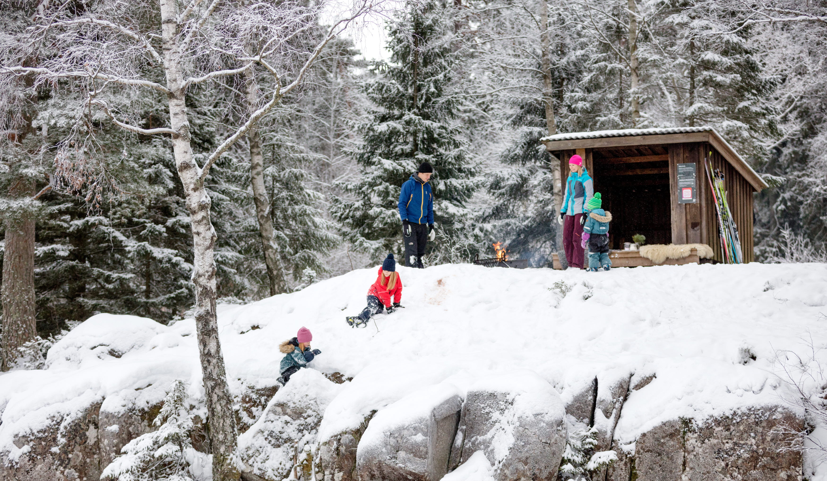 Family sitting by the fire surrounded by a winter landscape at Billingen moutain. 