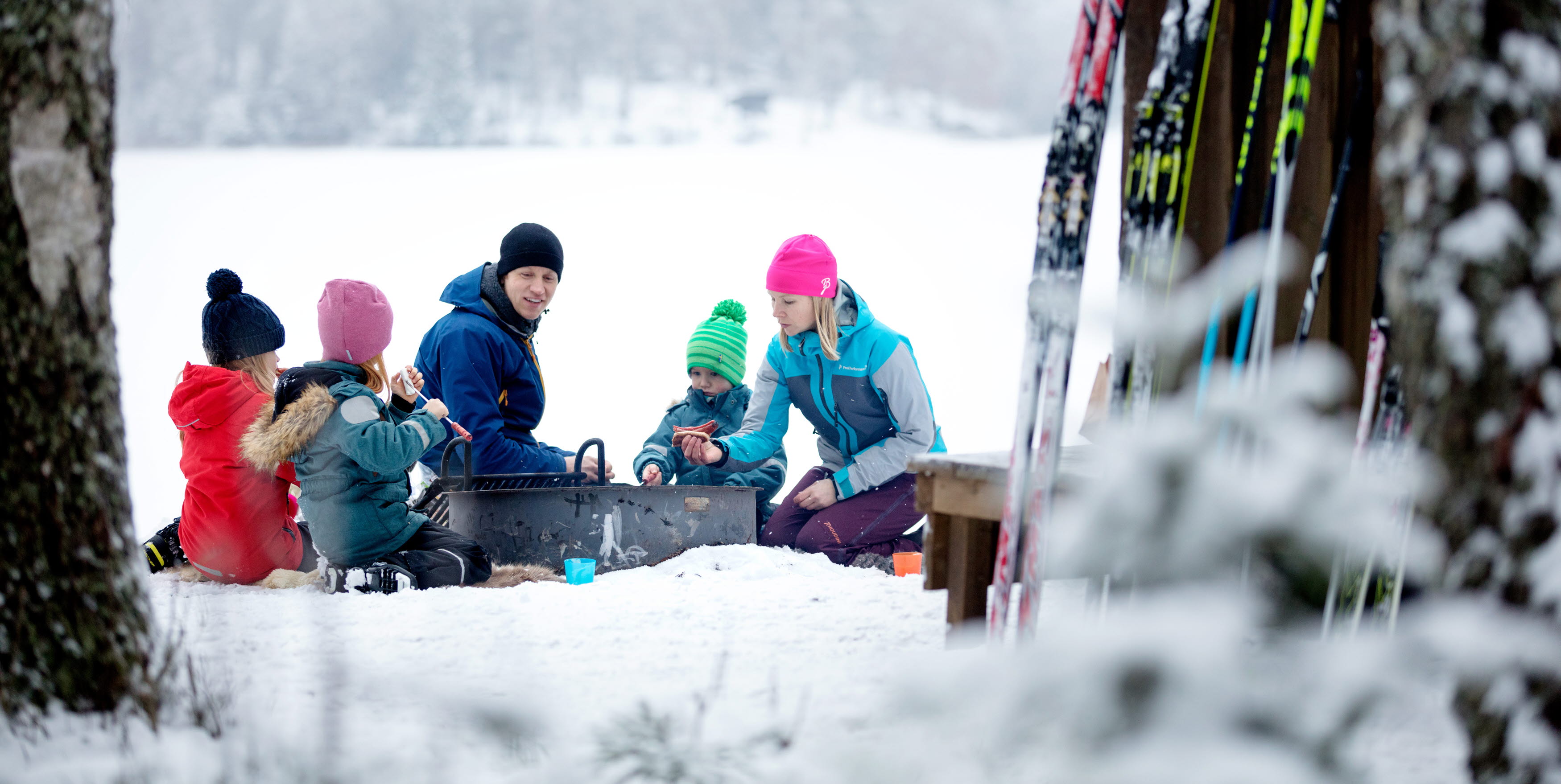 Family sitting by the fire surrounded by a winter landscape at Billingen moutain in Skövde.