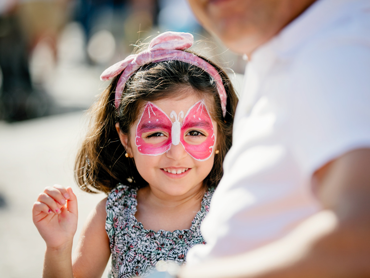 En glad tjej med rosa ansiktsmålning i form av en fjäril. 