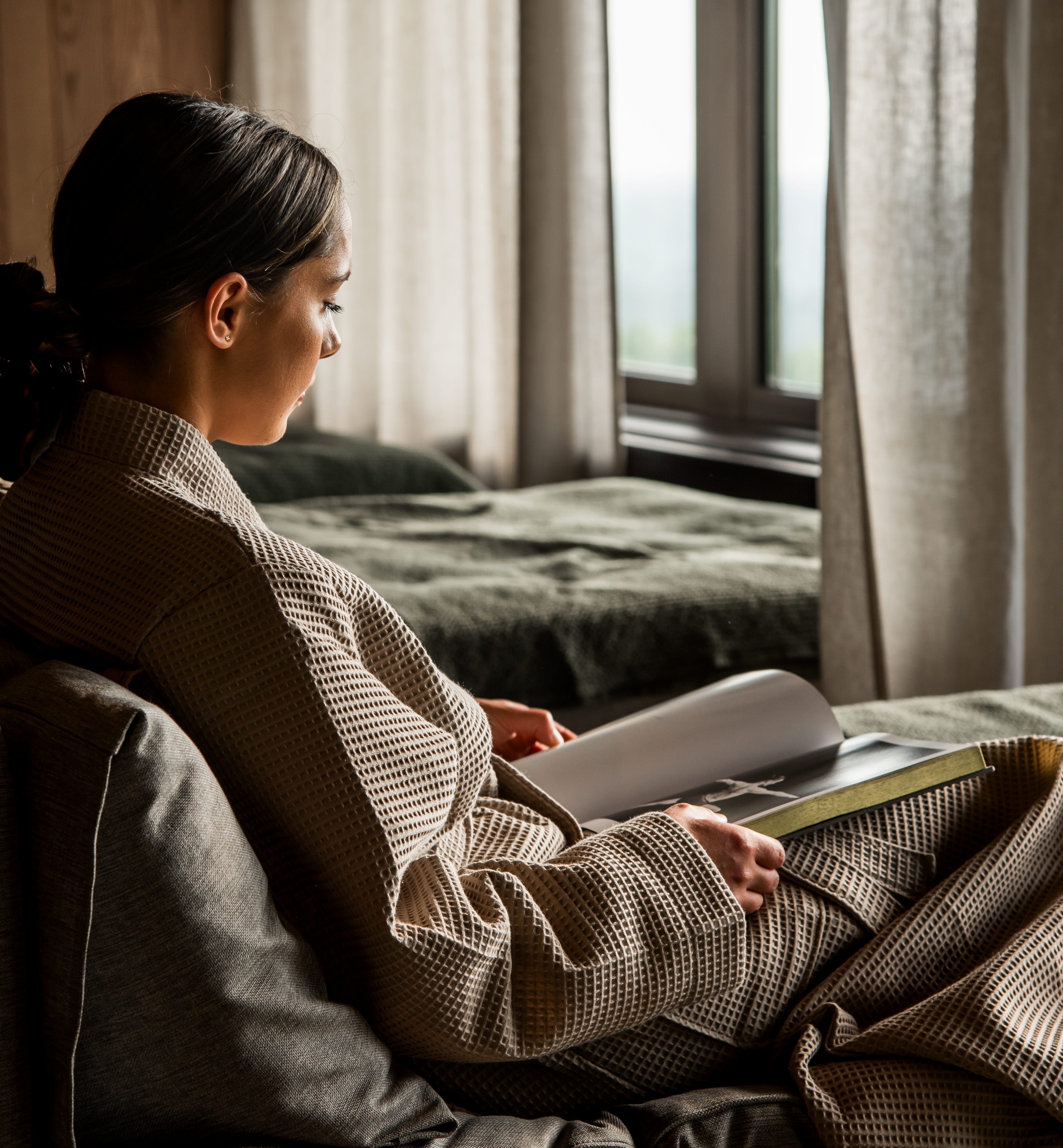 Kvinna i badrock sitter och tittar ner i en bok