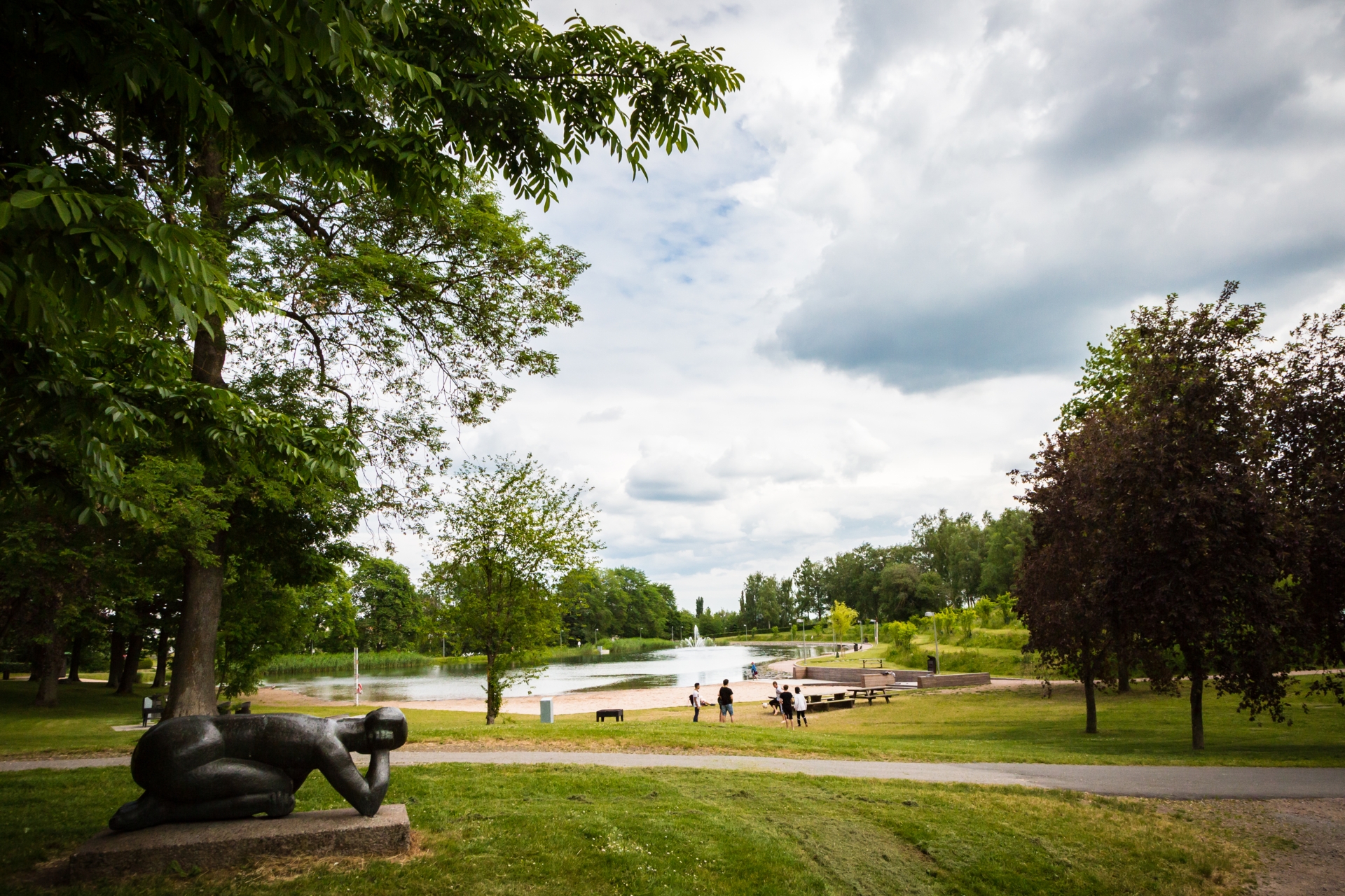 Grönska och staty i en park. I bakgrunden ligger badsjön Boulognersjön