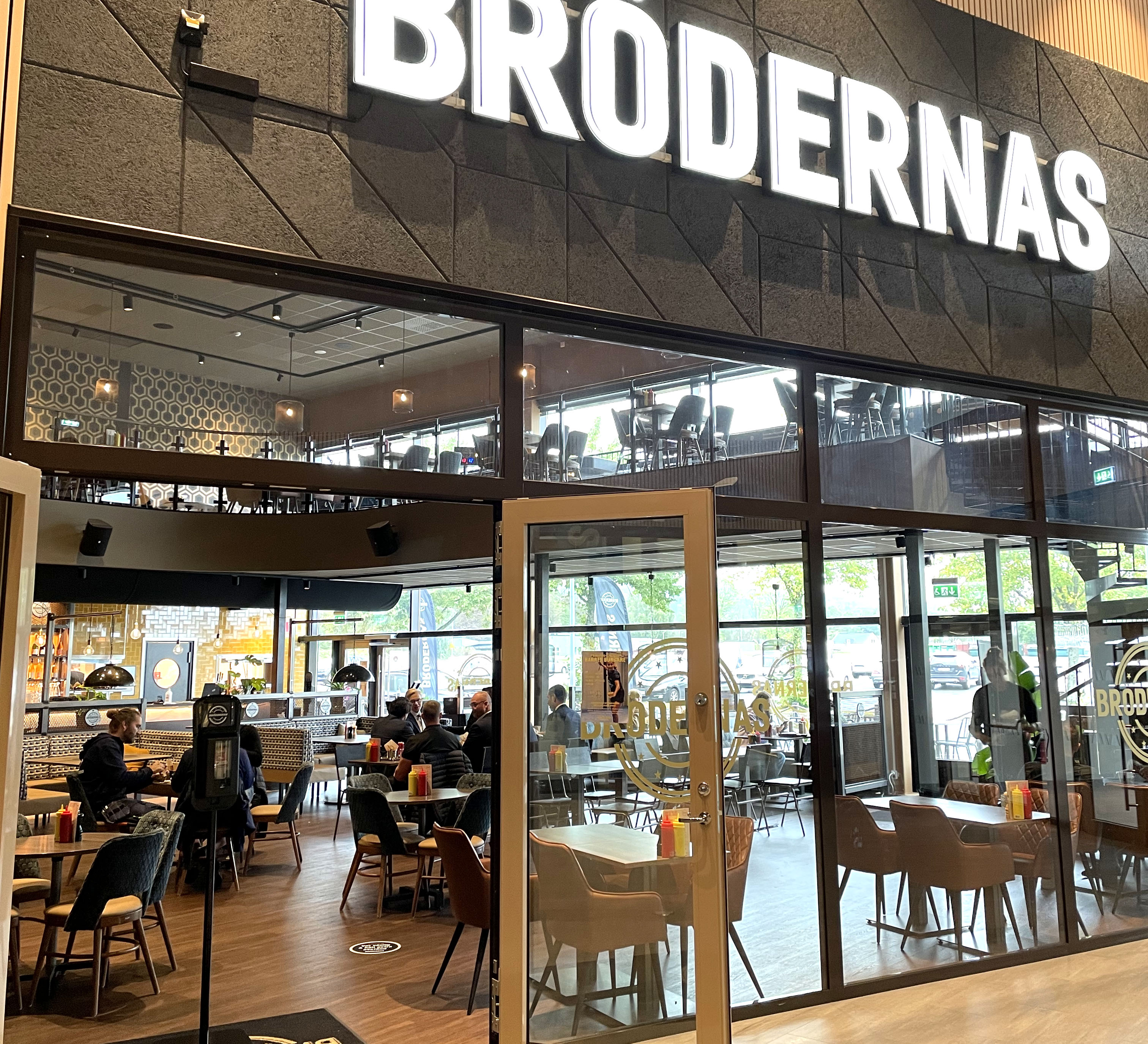 Glasväggar med en restaurang bakom. En stor skylt på väggen ovanför