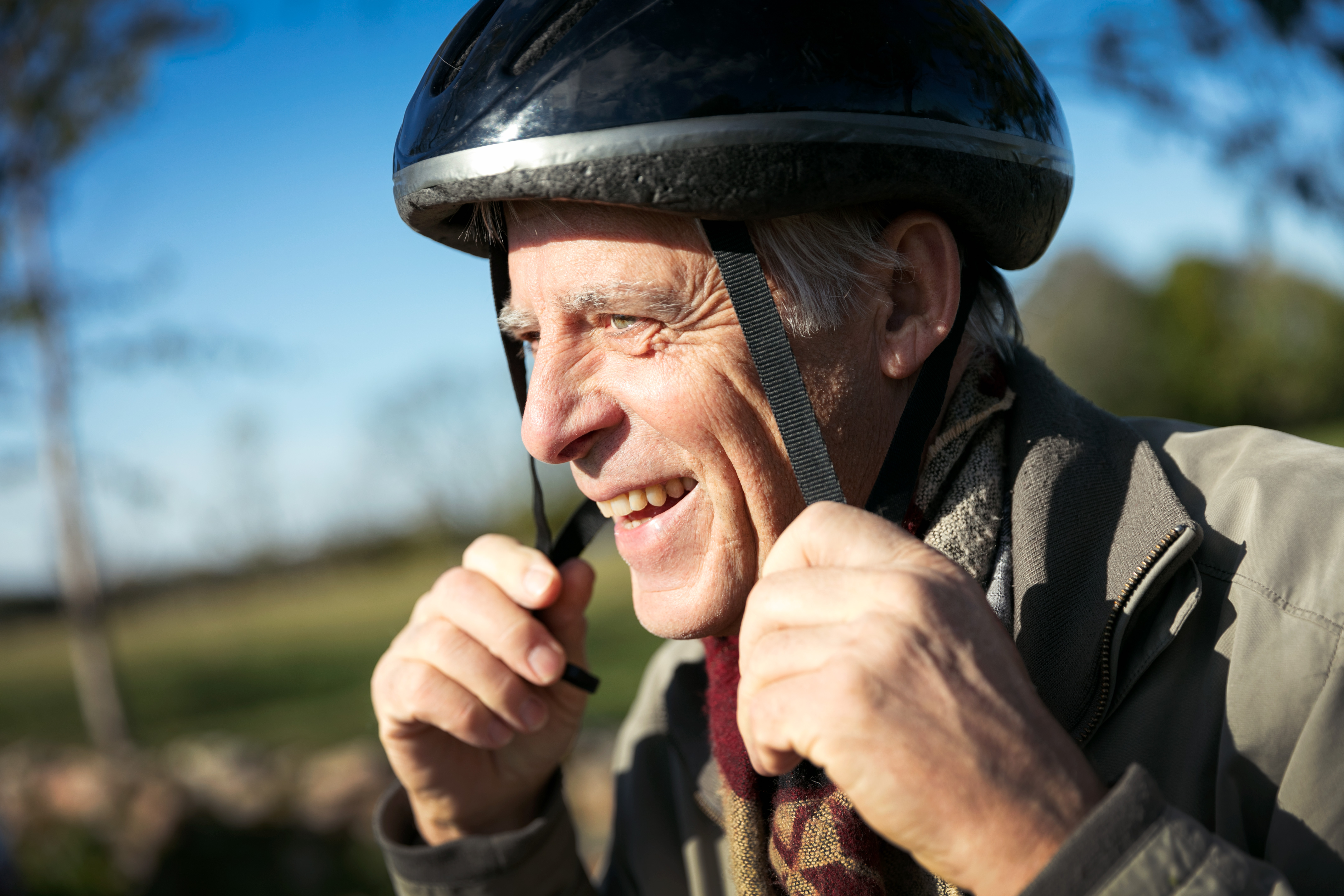 En man tar på sig en svart cykelhjälm.