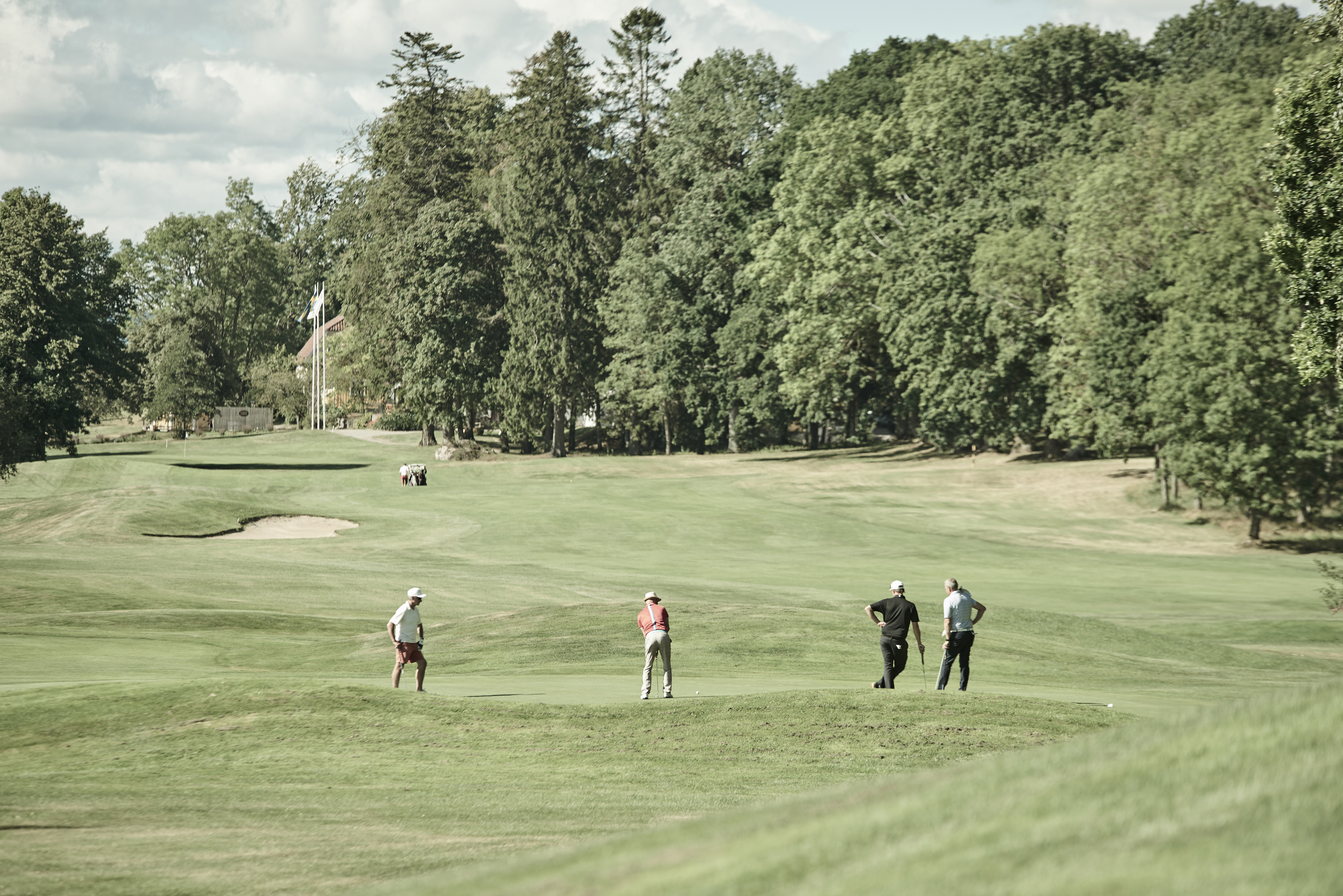 Golfbana med fyra personer som spelar golf, personerna är ganska långt bort i bilden.