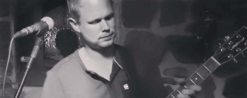 En man med gitarr och micstativ. 