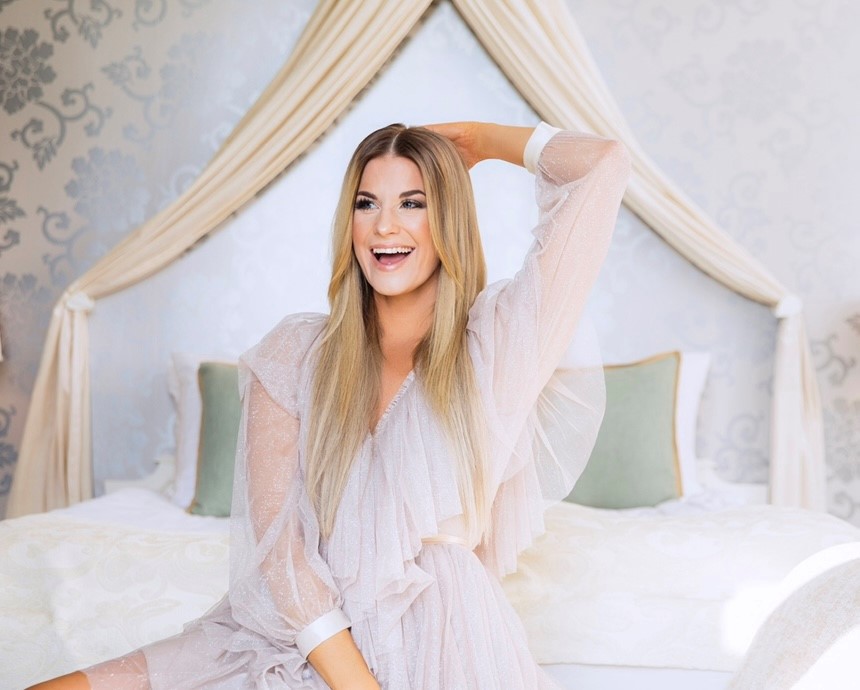 En tjej klädd i vitt på en säng. 