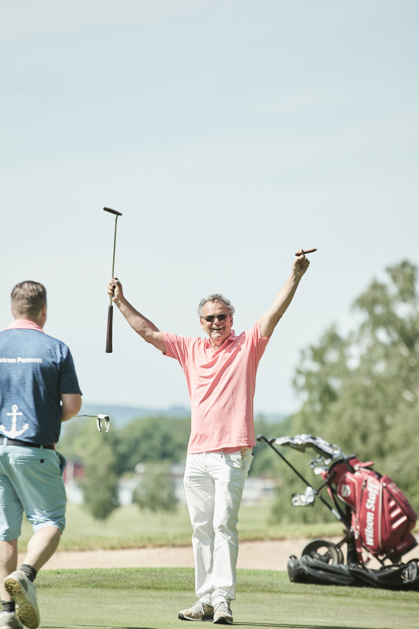 En bild på en jublande Steffo Törnkvist med en golfklubba i ena handen och en cigarr i andra.