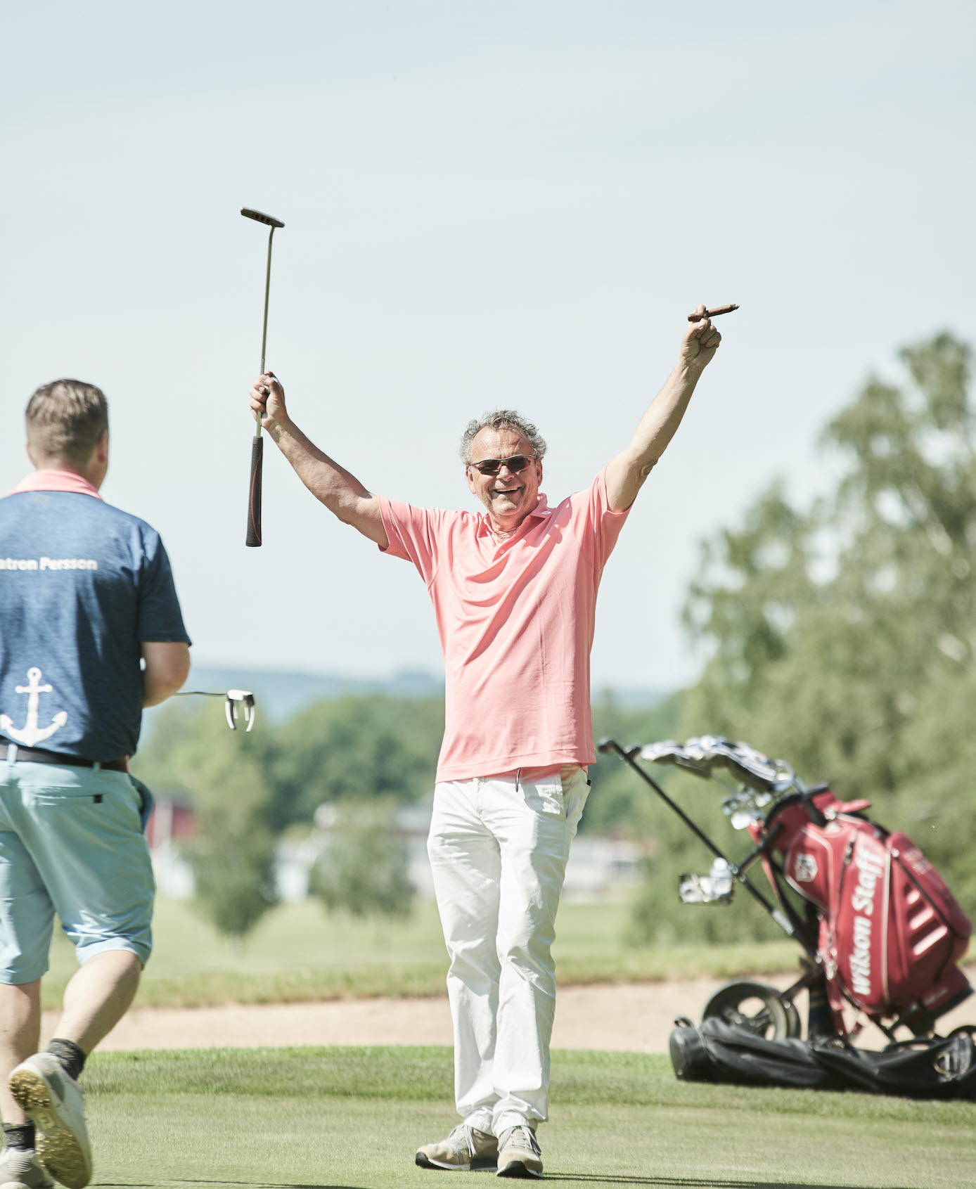 En bild på en jublande Steffo Törnkvist med en golfklubba i ena handen och en cigarr i andra.