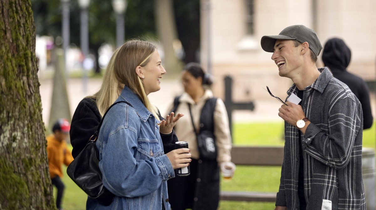 En tjej och en kille står och pratar med varandra och skrattar. 