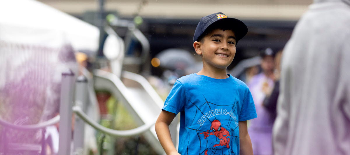 En glad kille med blå tshirt på en lekplats. 