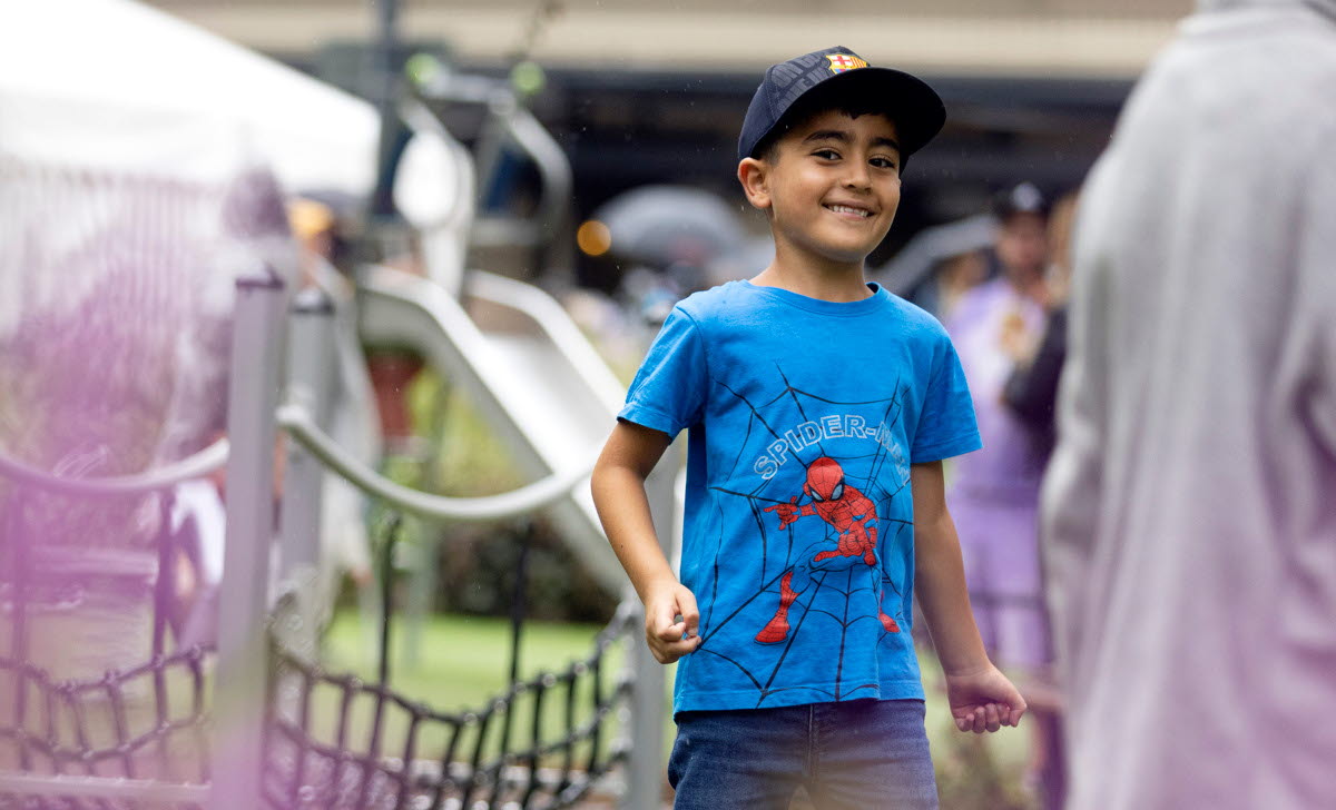 En glad kille med blå tshirt på en lekplats. 