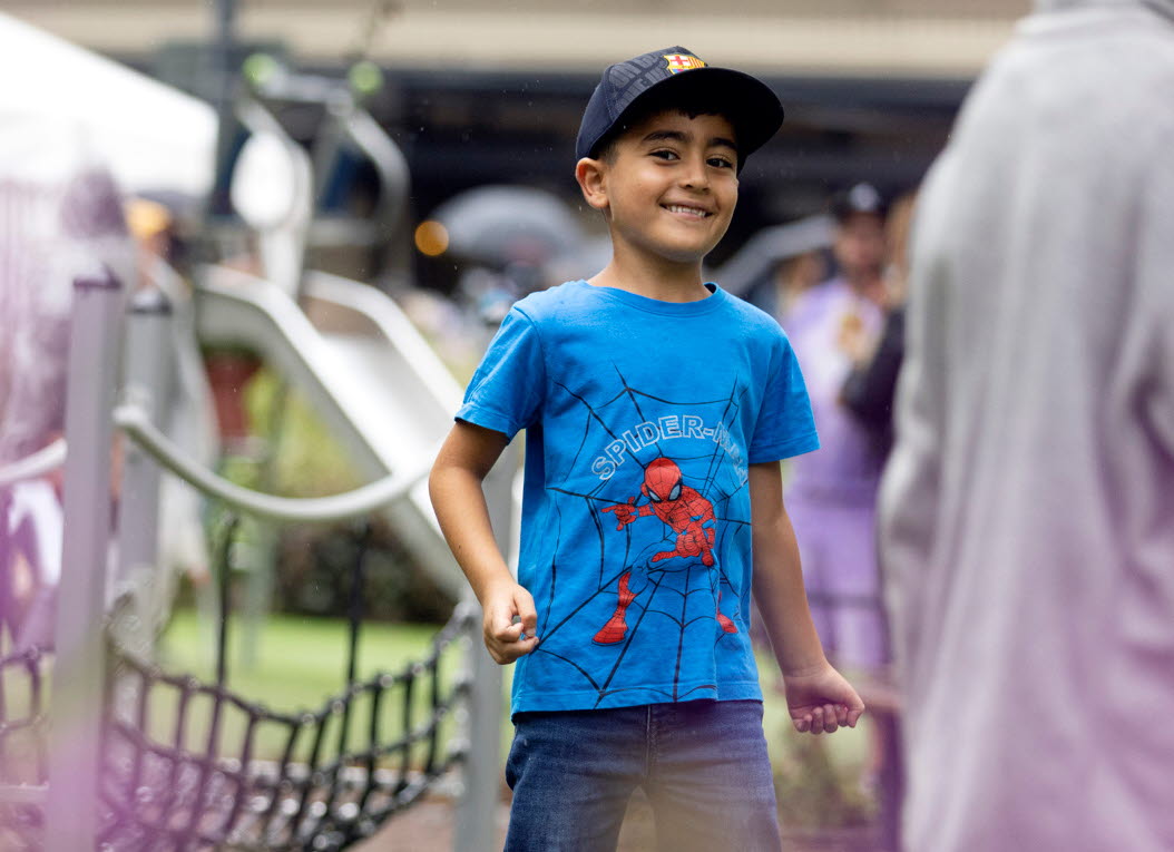 En glad kille med blå tshirt på en lekplats. 