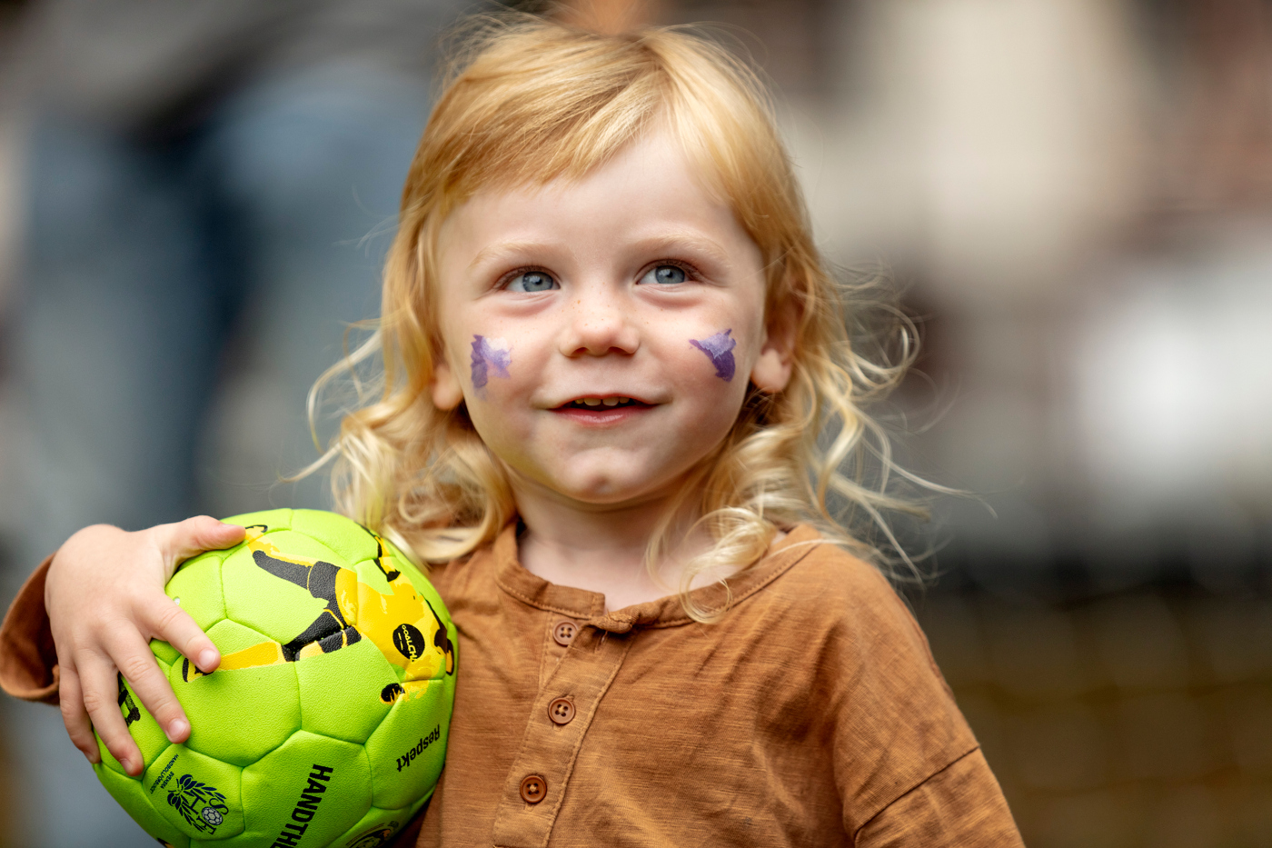 Glad liten tjej som håller en handboll