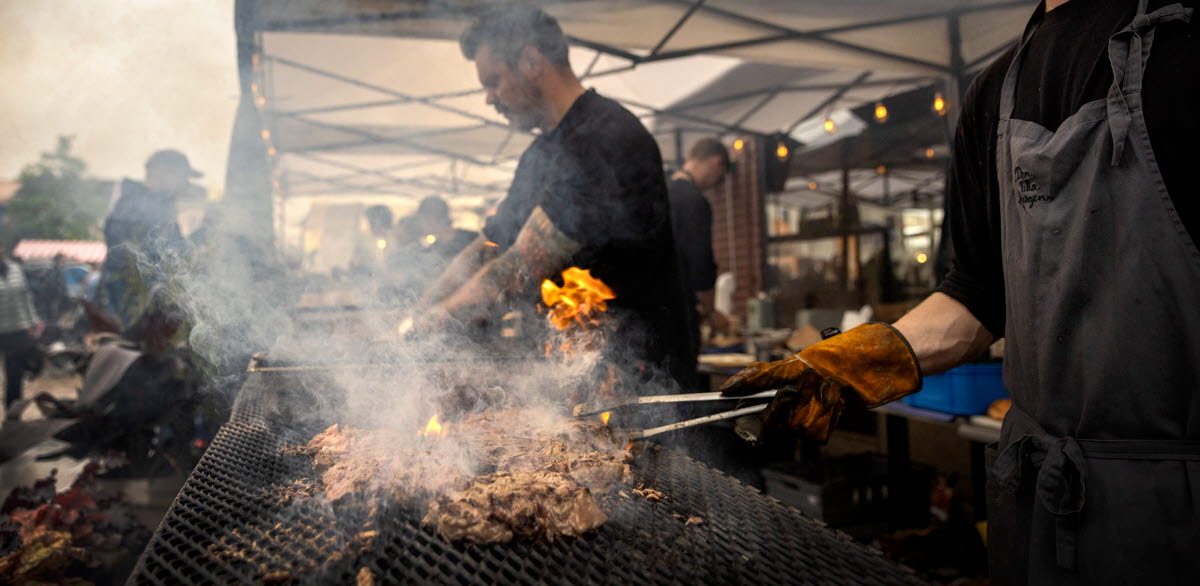 Två män grillar kött. 