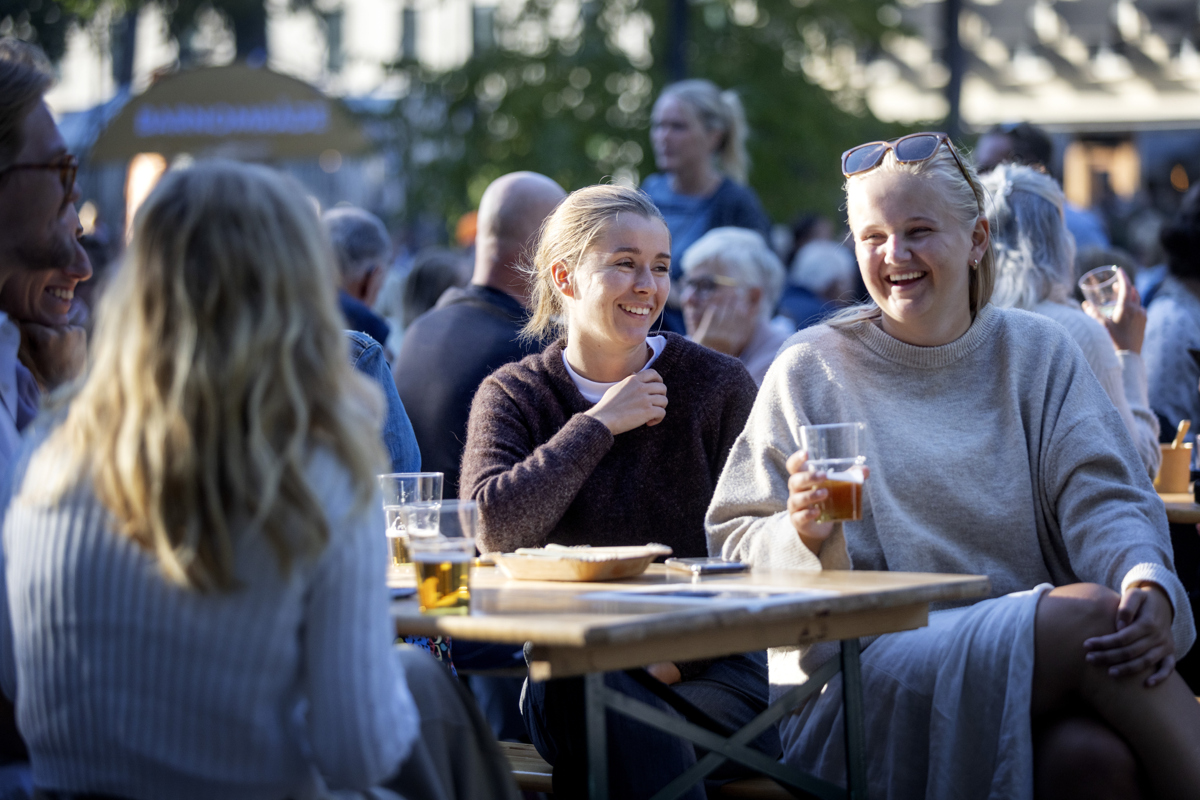 Två glada tjejer sitter vid ett bord i ett folkmyller.