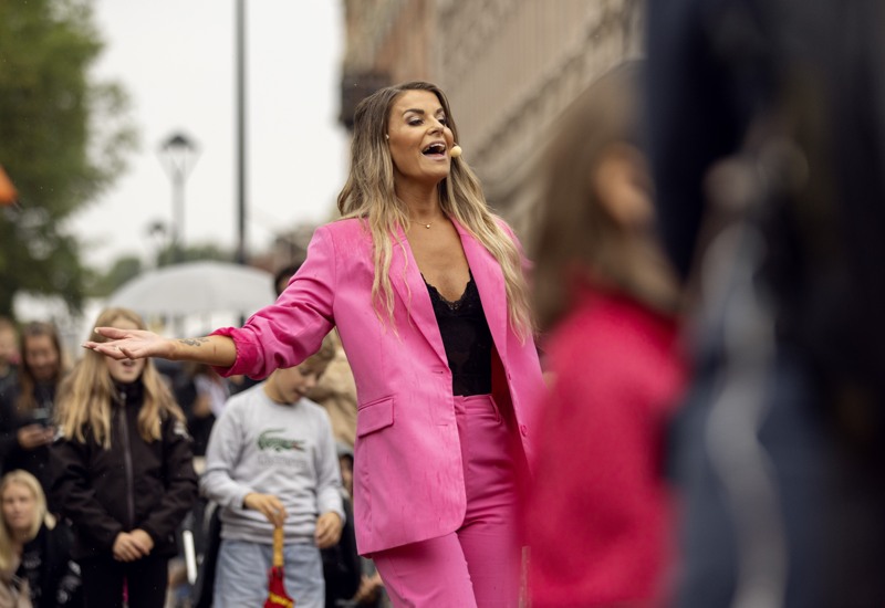 En tjej i rosa kostym med människor runt sig.