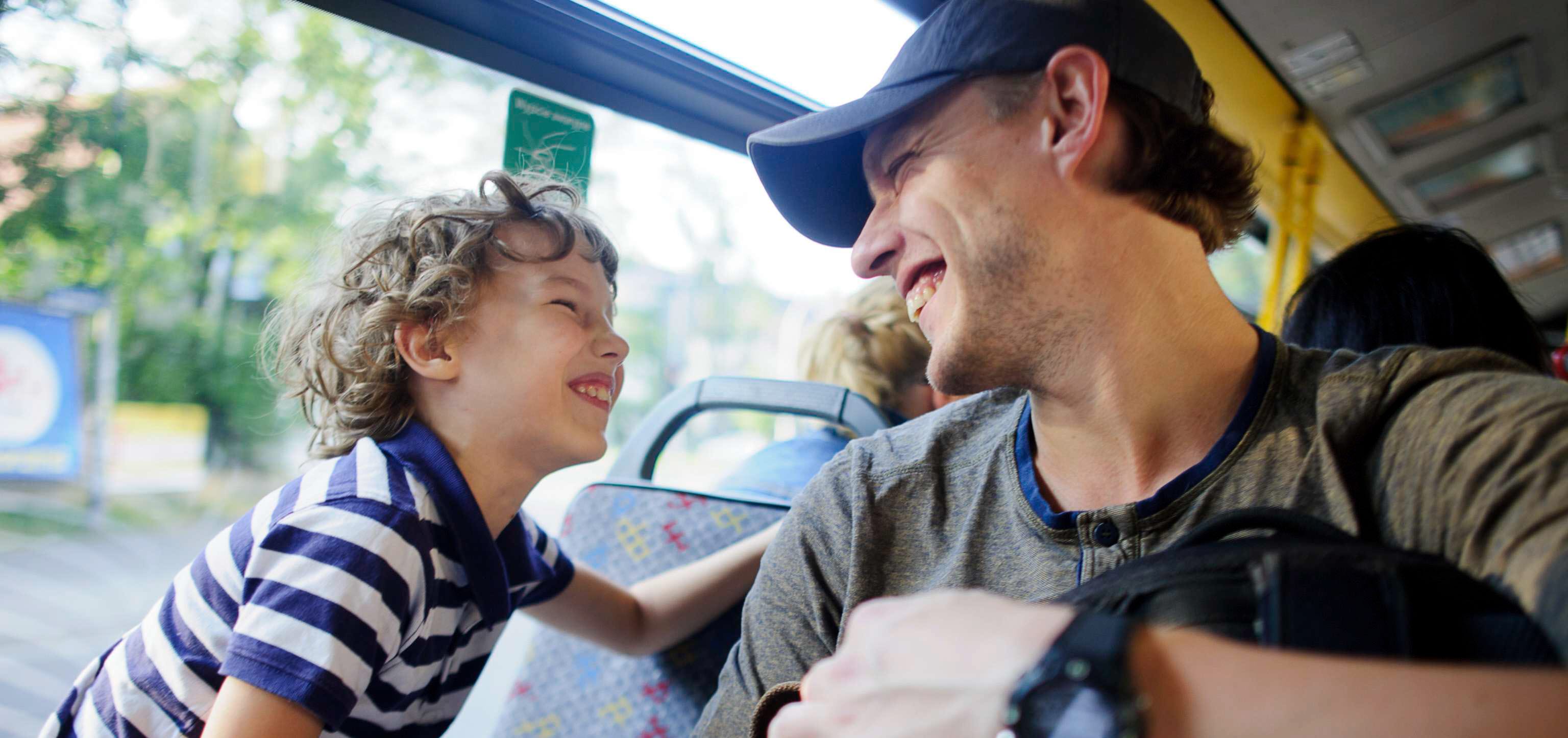 En skrattade liten kille med sin pappa på buss.