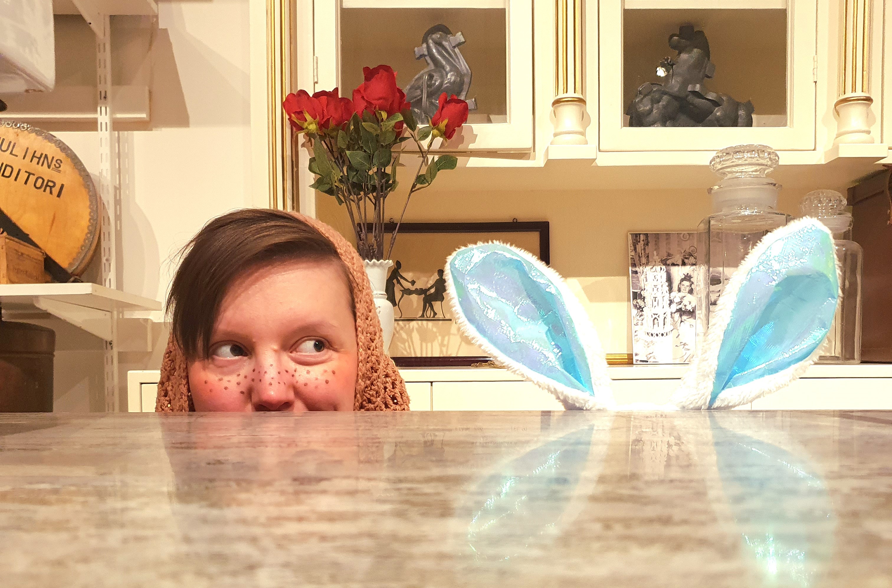 En påskkärring och påskharens öron kikar upp bakom en kafédisk. 