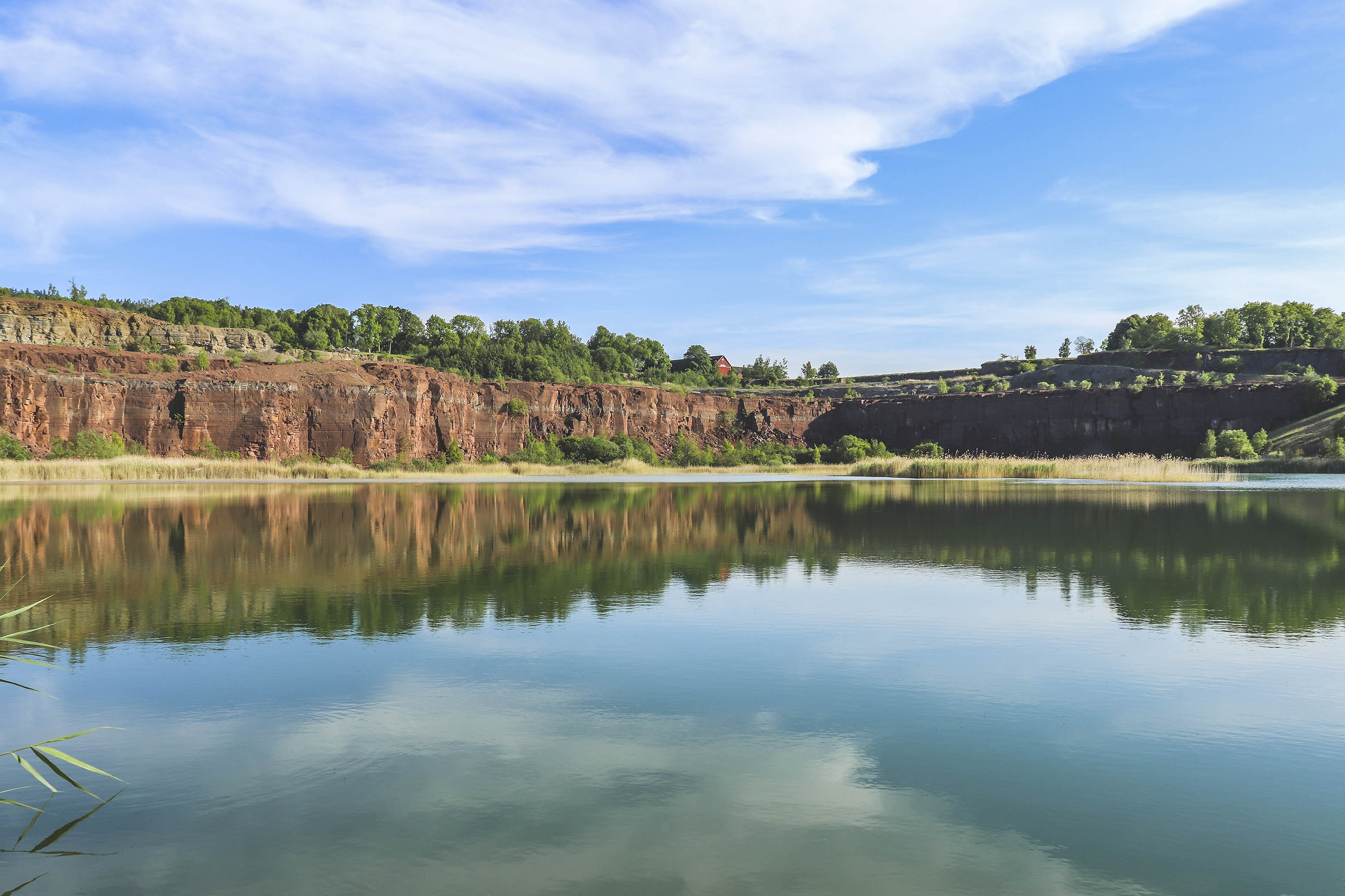 Vacker vy med blå himmel och spegelblankt vatten vid stenbrottet på Kinnekulle. 
