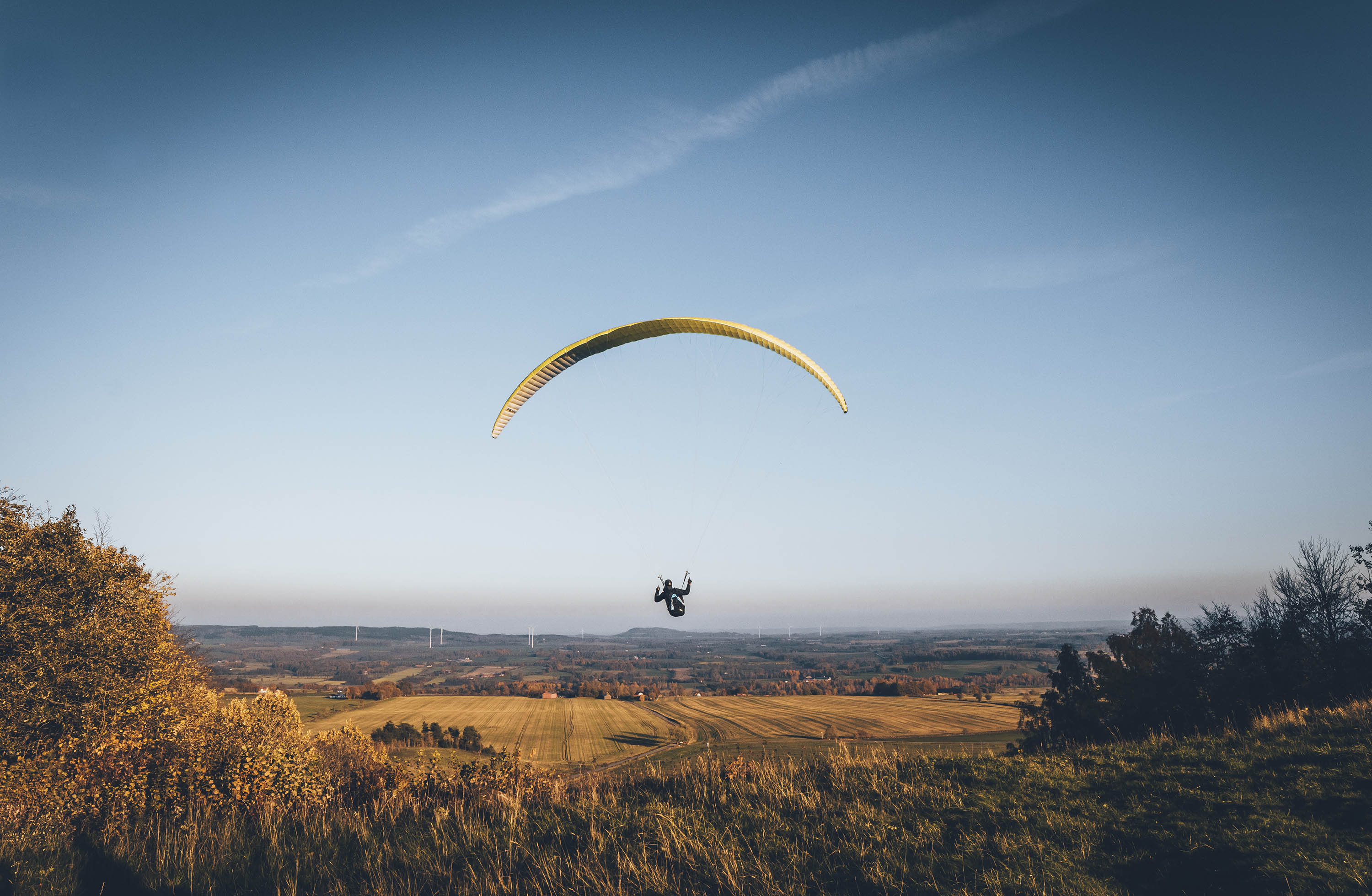 Med en klarblå himmel och öppet landskap vindseglar en person ut över vidderna. 