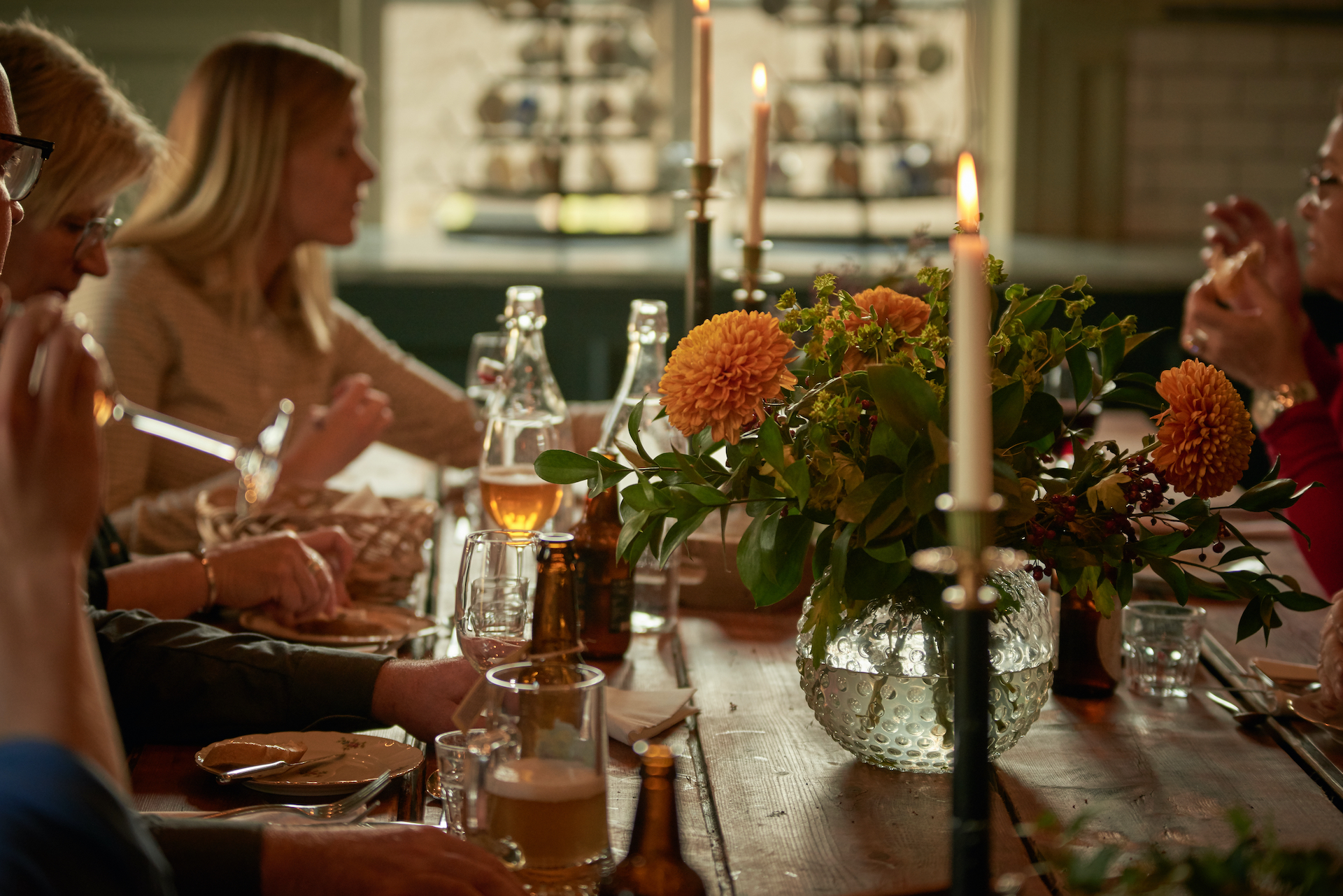 Ett bord med levande ljus, blommor och kvinnor som äter mat. 