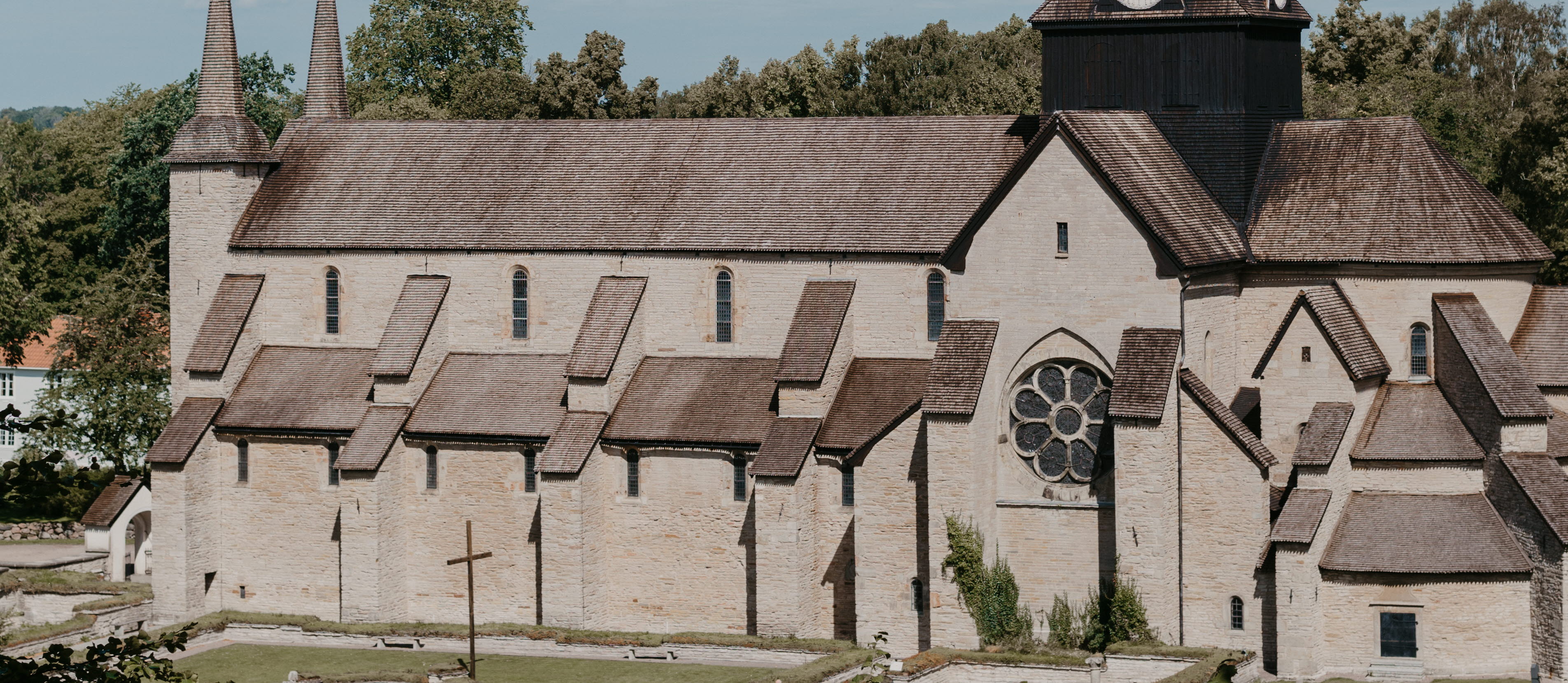 En klosterkyrka med ett högt torn i tjärat trä. Himlen är blå.