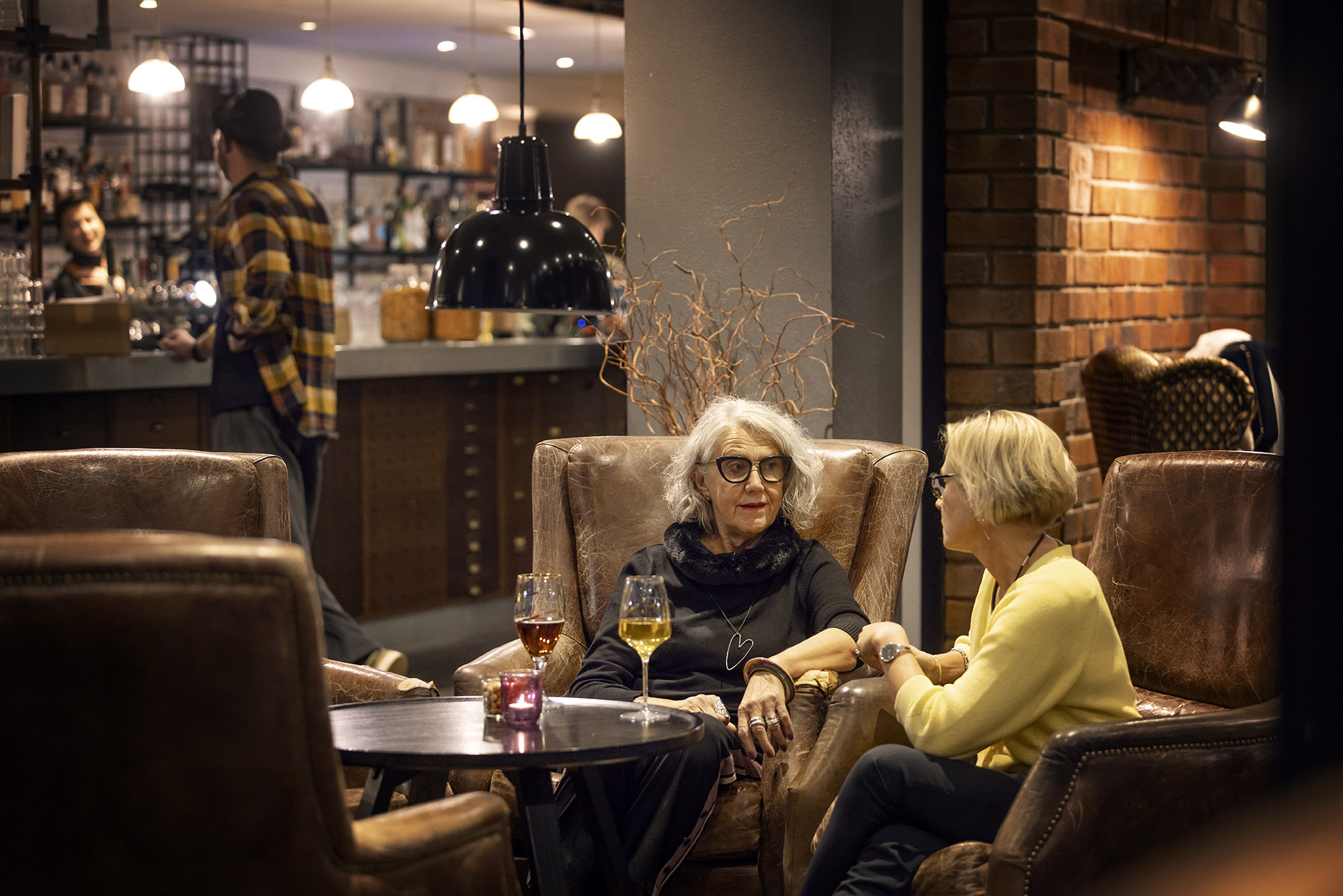 Två damer i varsin fåtölj i en bar. 